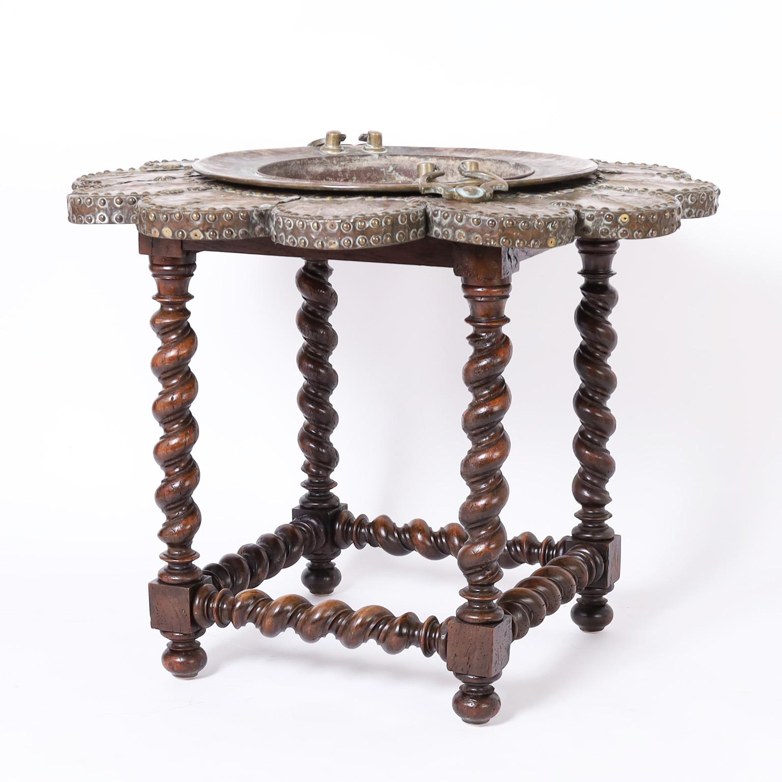 Intriguing 19th century English table with a hand crafted copper brazier surrounded by brass tacked pedals with plenty of wear on a carved and turned barley twist walnut base.
