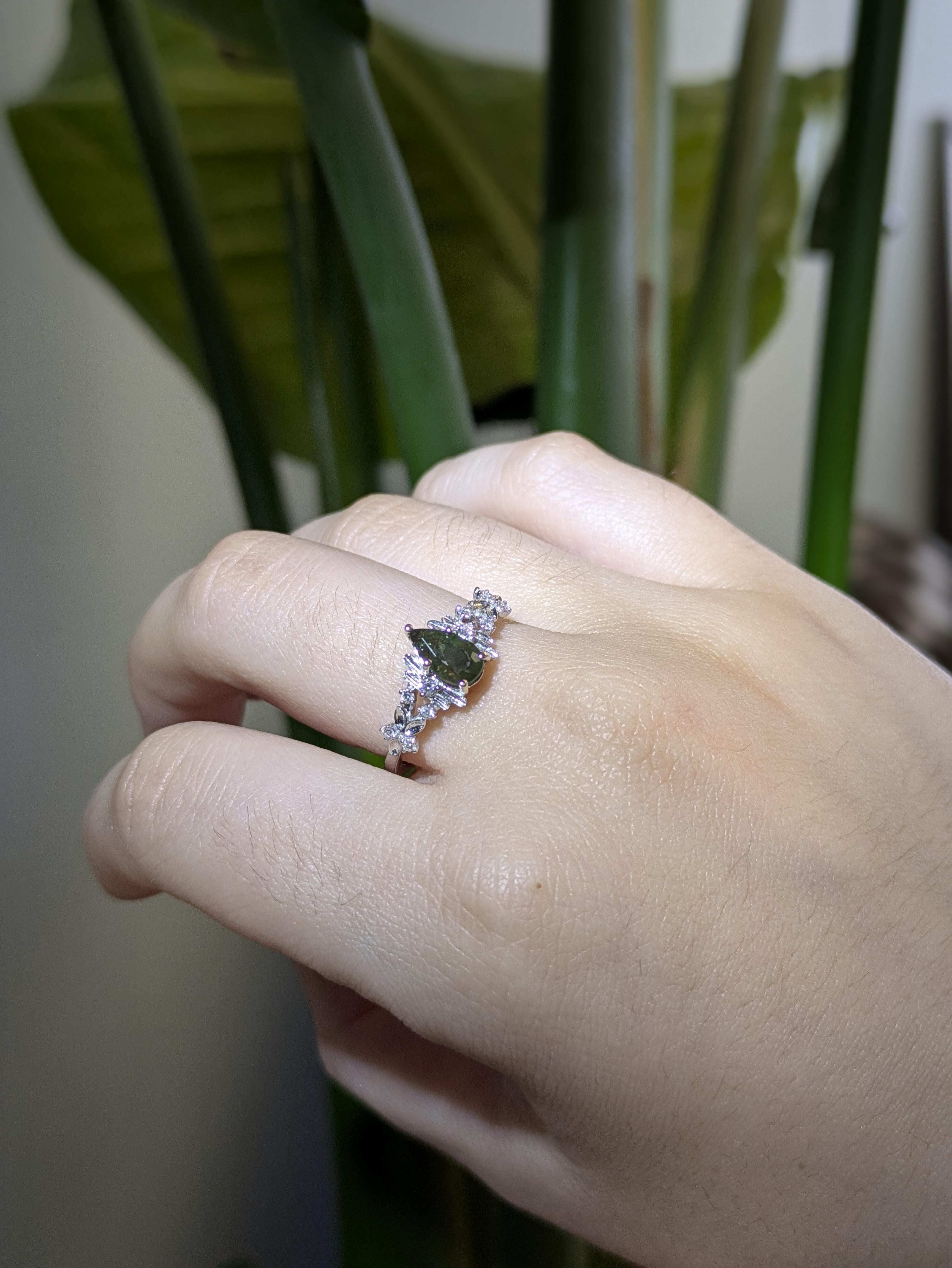 A stunning 8x4.5mm pear-shaped Alexandrite shimmers between hues of green and violet, framed by sparkling earth-mined diamonds in solid 14k white gold—a romantic, color-shifting beauty made for unforgettable moments.

