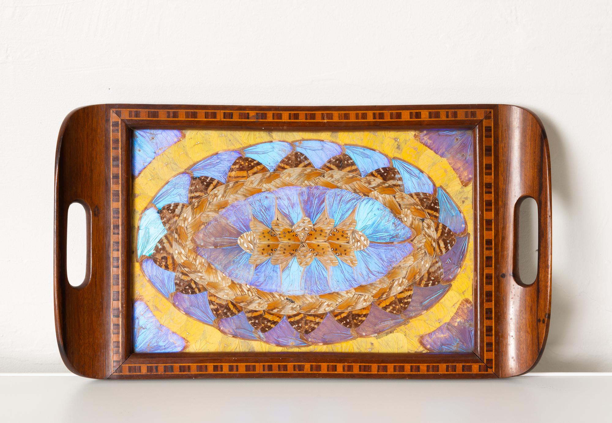Inlaid butterfly wing serving tray by Formanek, Brazil, circa 1950s. Featuring a stunning vibrant display of butterfly wings underneath a protective piece of glass, when the light hits the iridescent surface of the wings, this piece is truly