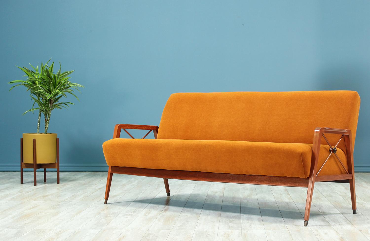 Sophisticated sofa manufactured by Cavallaro in Brazil circa 1960’s. This sofa features a frame made with exotic Caviuna wood and reupholstered in a persimmon colored mohair fabric. This elegant model features bronze feet tips and bronze medallions