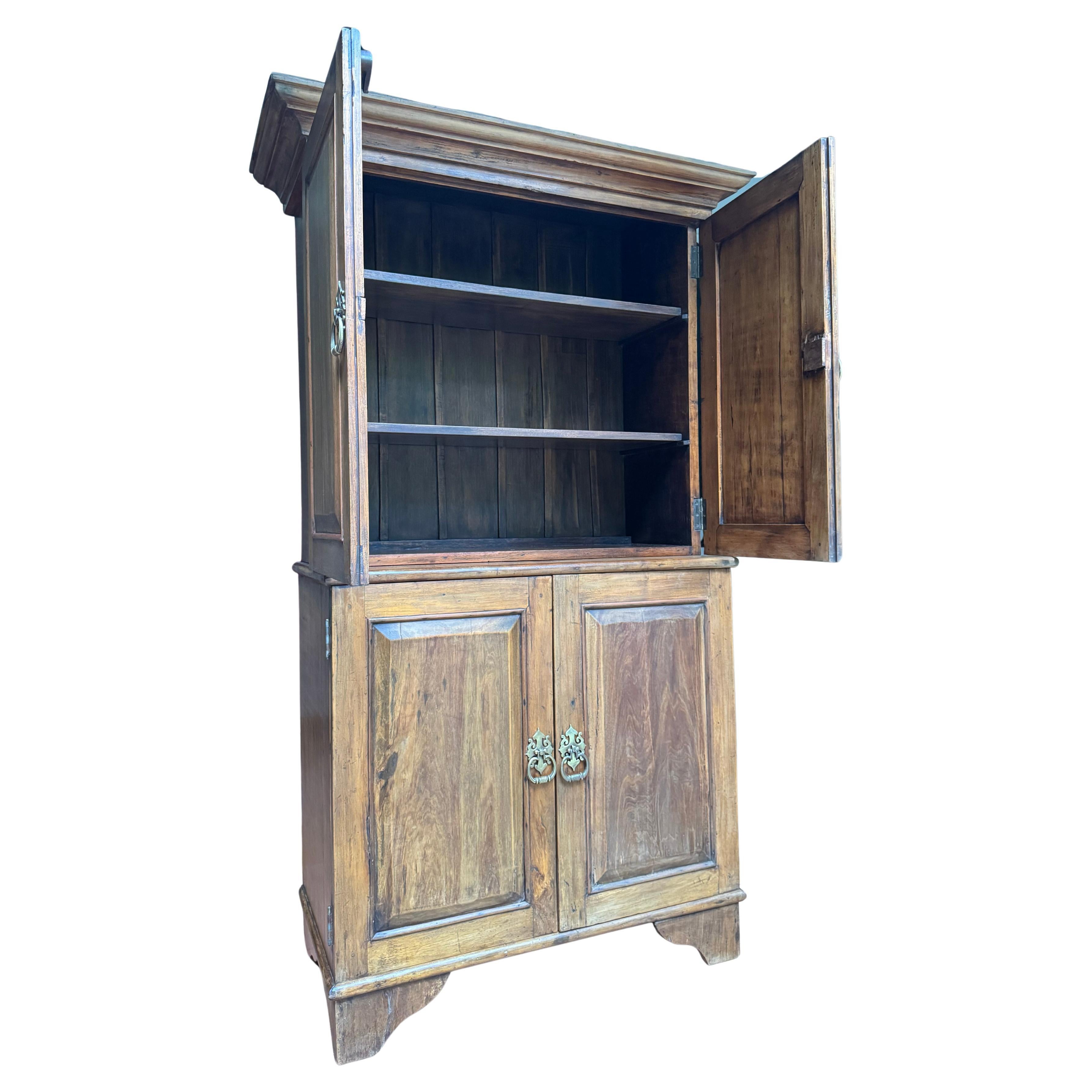 A fine example of Brazilian colonial revival craftsmanship, this two-part cupboard from the early 20th century evokes the solid dignity and balanced proportions of 18th-century furniture from the rural manors of Minas or Bahia. Built around