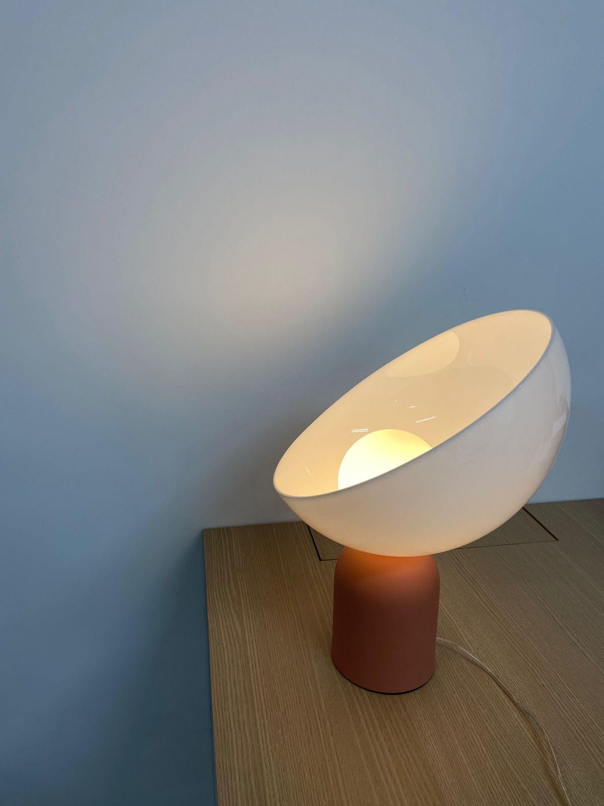 This table lamp is named Lichia. 
The product consists of a round acrylic diffuser and an aluminum base.
The base is in painted aluminum, and can be in any color from the palette posted in the photos (white, ivory, off-white pink, sand, avocado