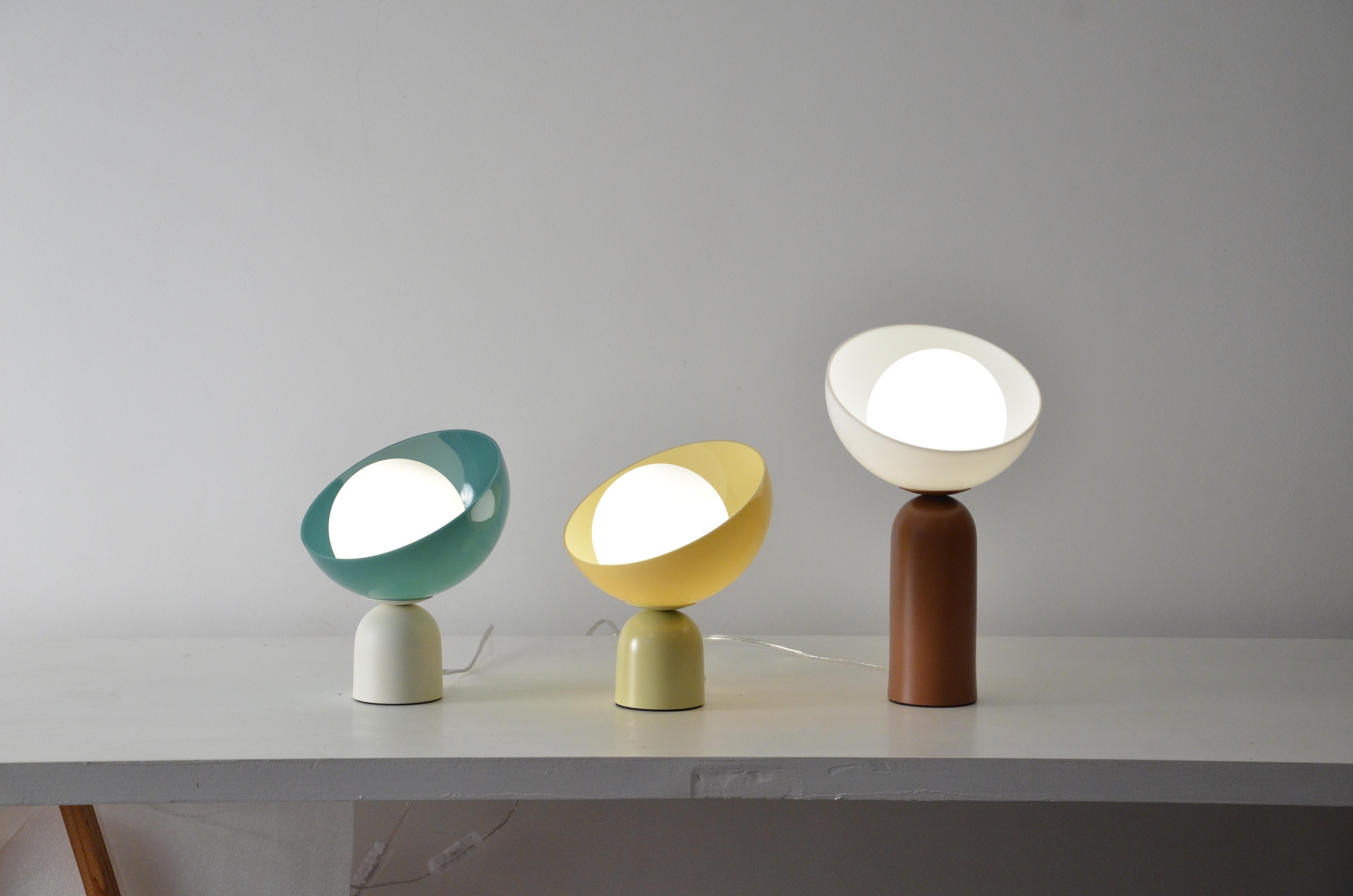 This table lamp is named Lichia. 
The product consists of a round acrylic diffuser and an aluminum base.
The base is in painted aluminum, and can be in any color from the palette posted in the photos (white, ivory, off-white pink, sand, avocado