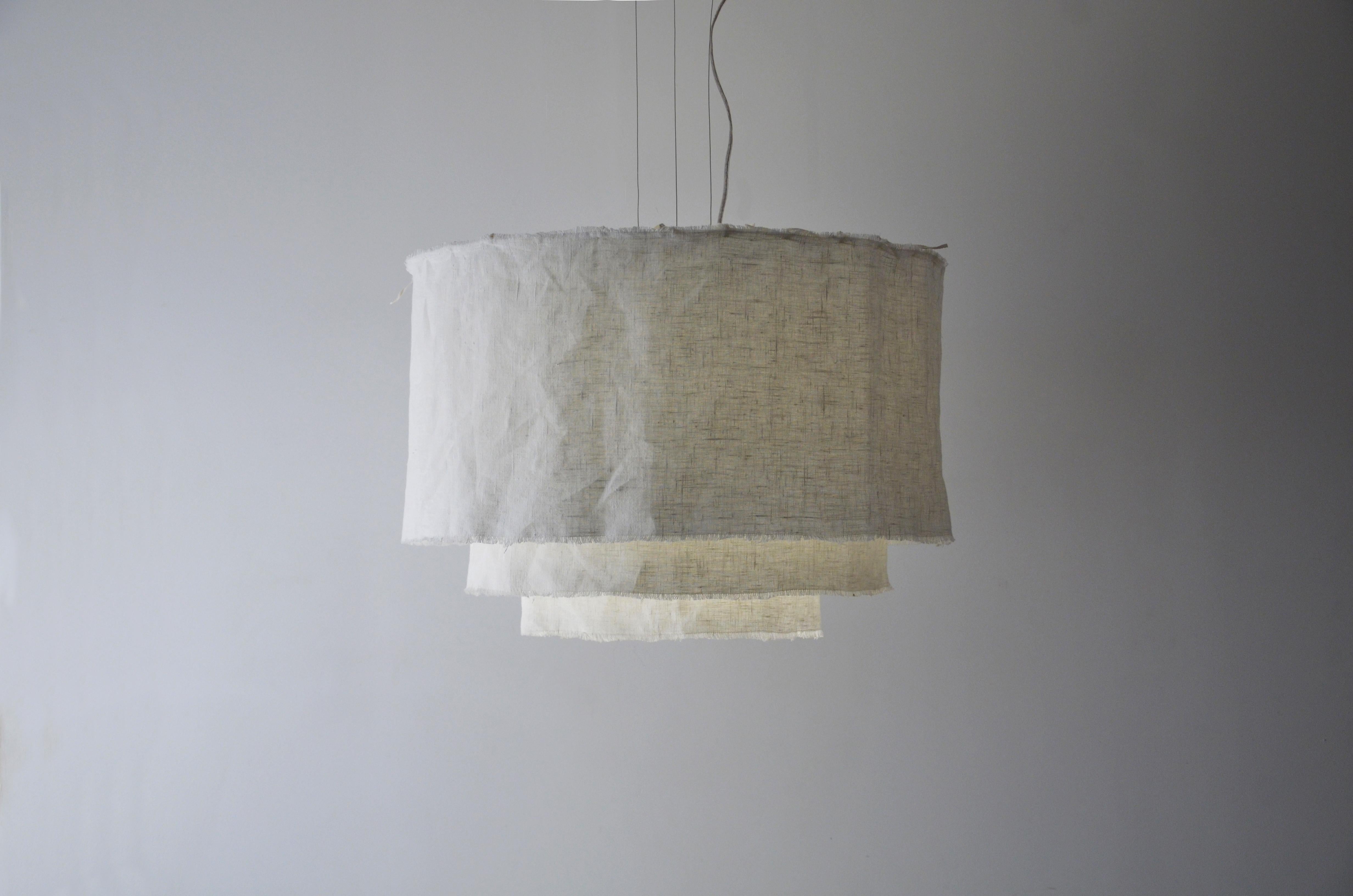 This pendant is named Acítara. 
It has three layers, one longer than the other, and it is made in prewashed white linen. The structure of the product is made of white alumnium. 
The linen can me dry cleaned, because it is prewashed. 
It has 90cm of