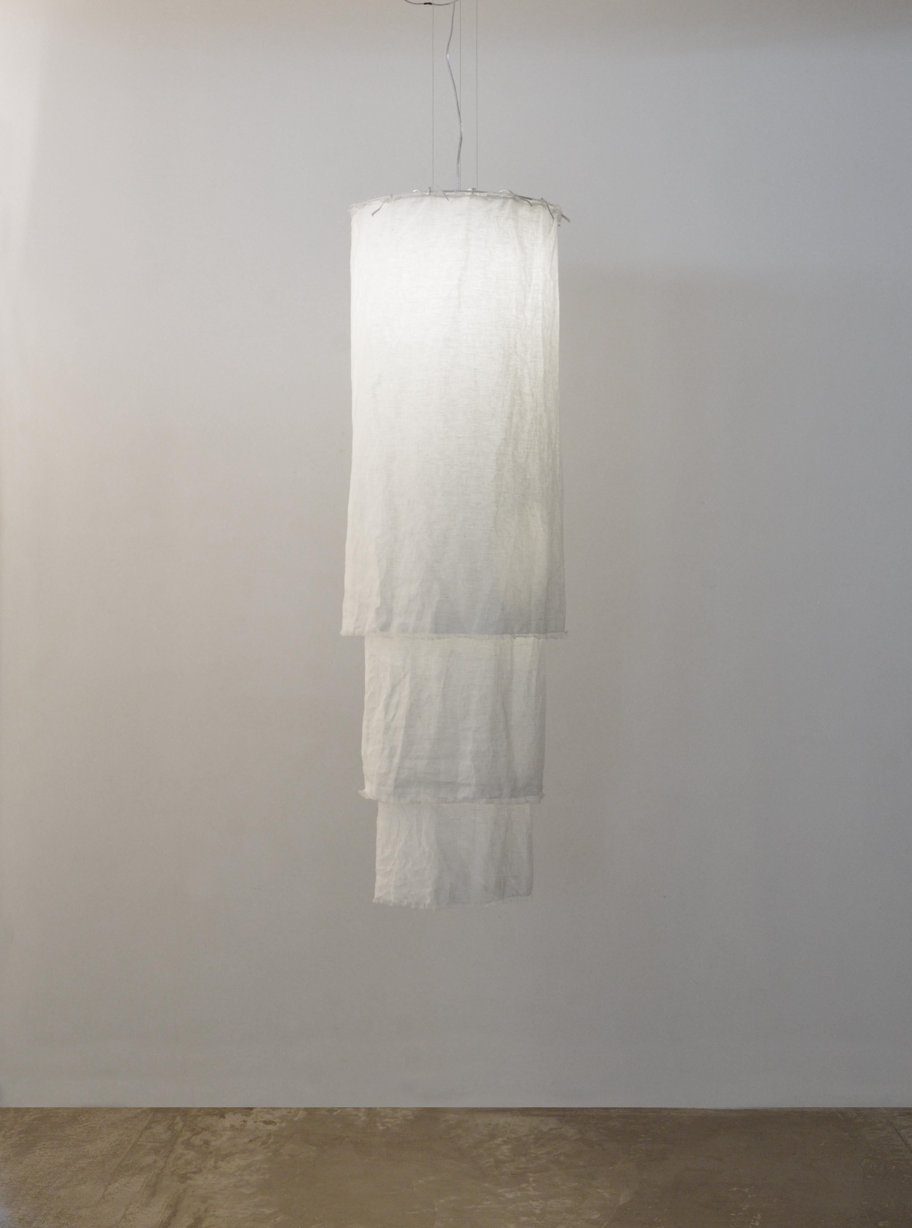 This pendant is named Acítara. 
It has three layers, one longer than the other, and it is made in prewashed white linen. The structure of the product is made of white alumnium. 
The linen can me dry cleaned, because it is prewashed. 
It has 40cm of