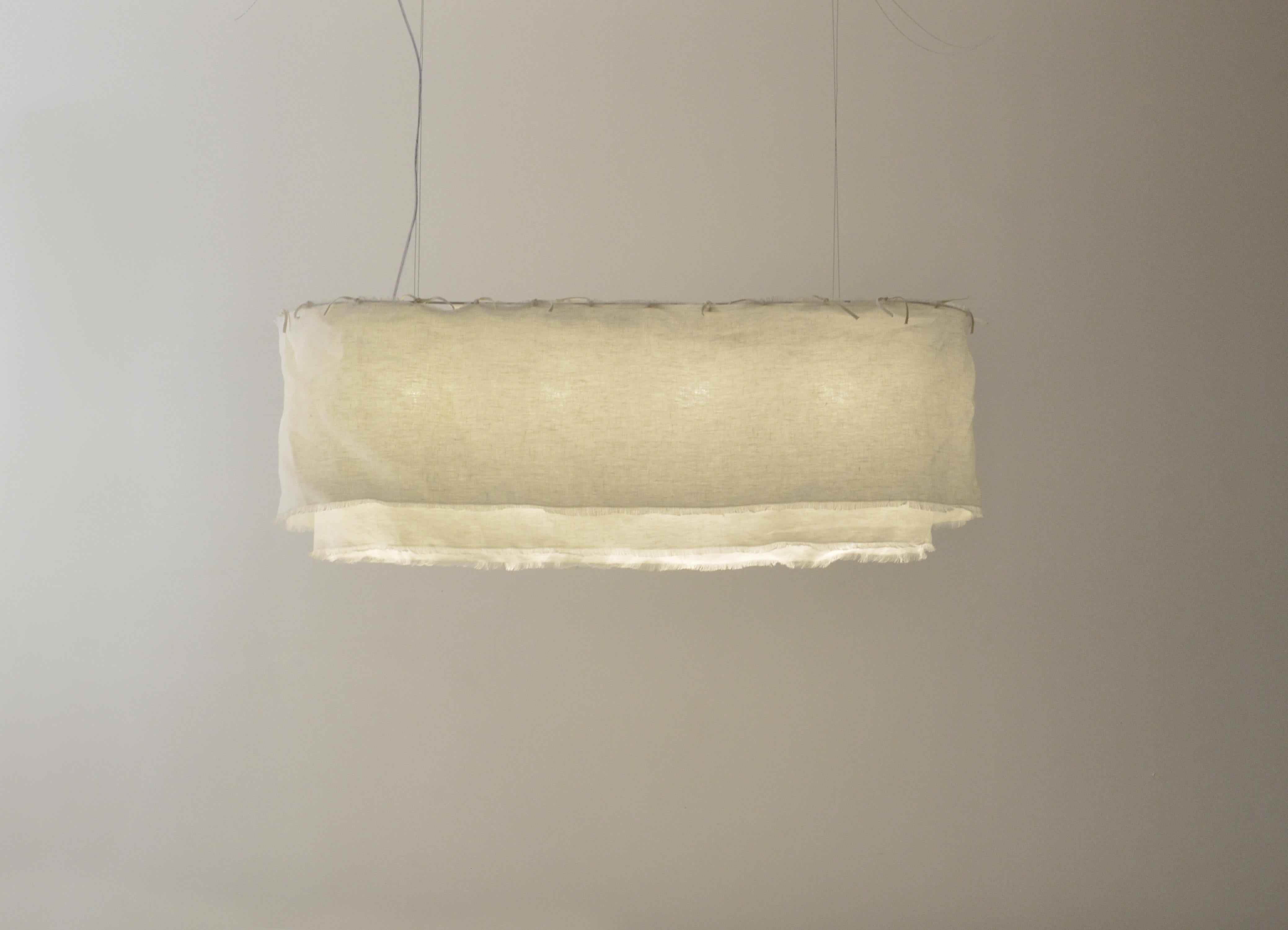 Questo ciondolo si chiama Acítara. 
Ha due strati, uno più lungo dell'altro, ed è realizzato in lino bianco prelavato. La struttura del prodotto è realizzata in alluminio bianco. 
Il lino può essere lavato a secco, perché è prelavato. 
Ha le