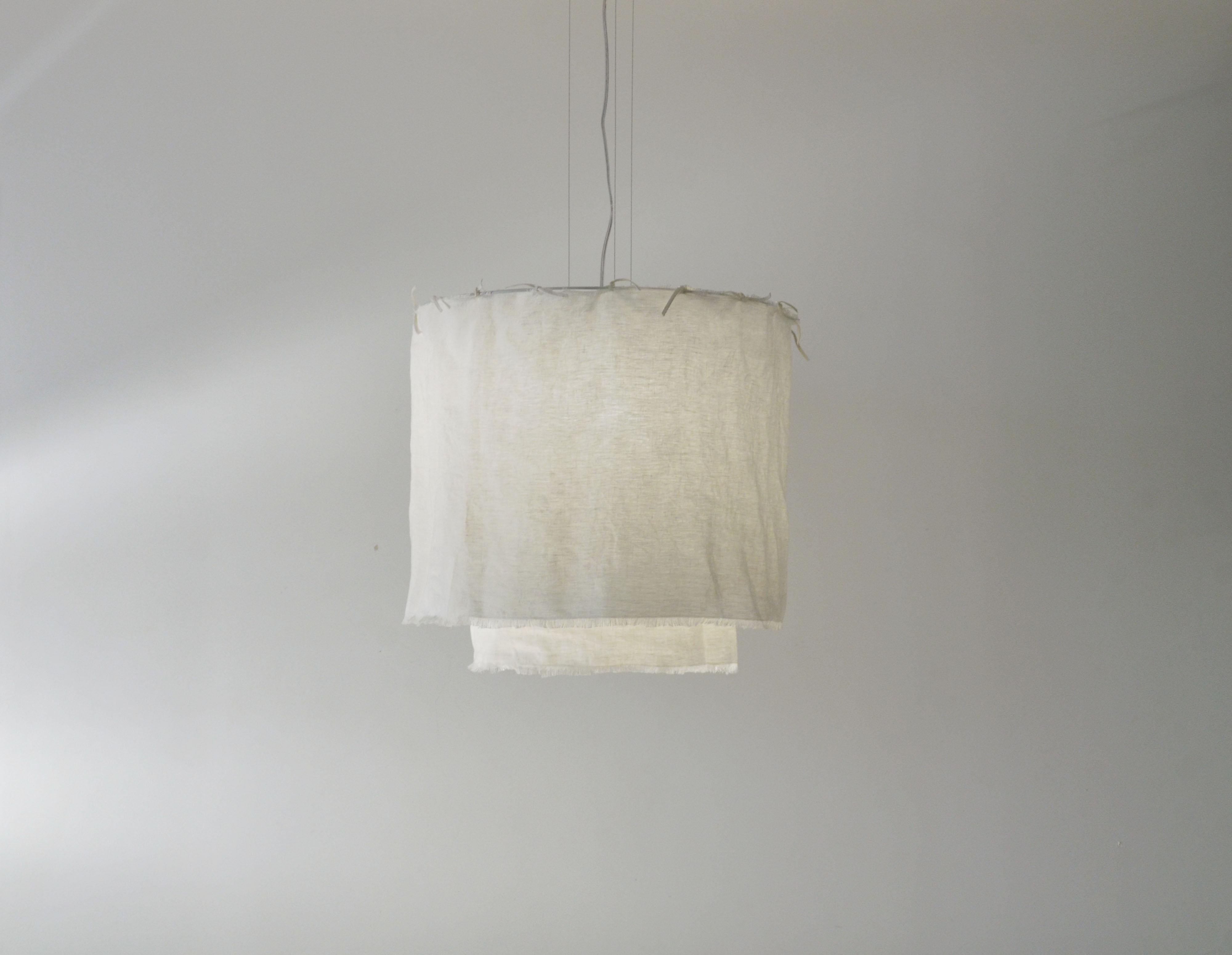 This pendant is named Acítara. 
It has two layers, one longer than the other, and it is made in prewashed white linen. The structure of the product is made of white alumnium. 
The linen can me dry cleaned, because it is prewashed. 
It has 50cm of