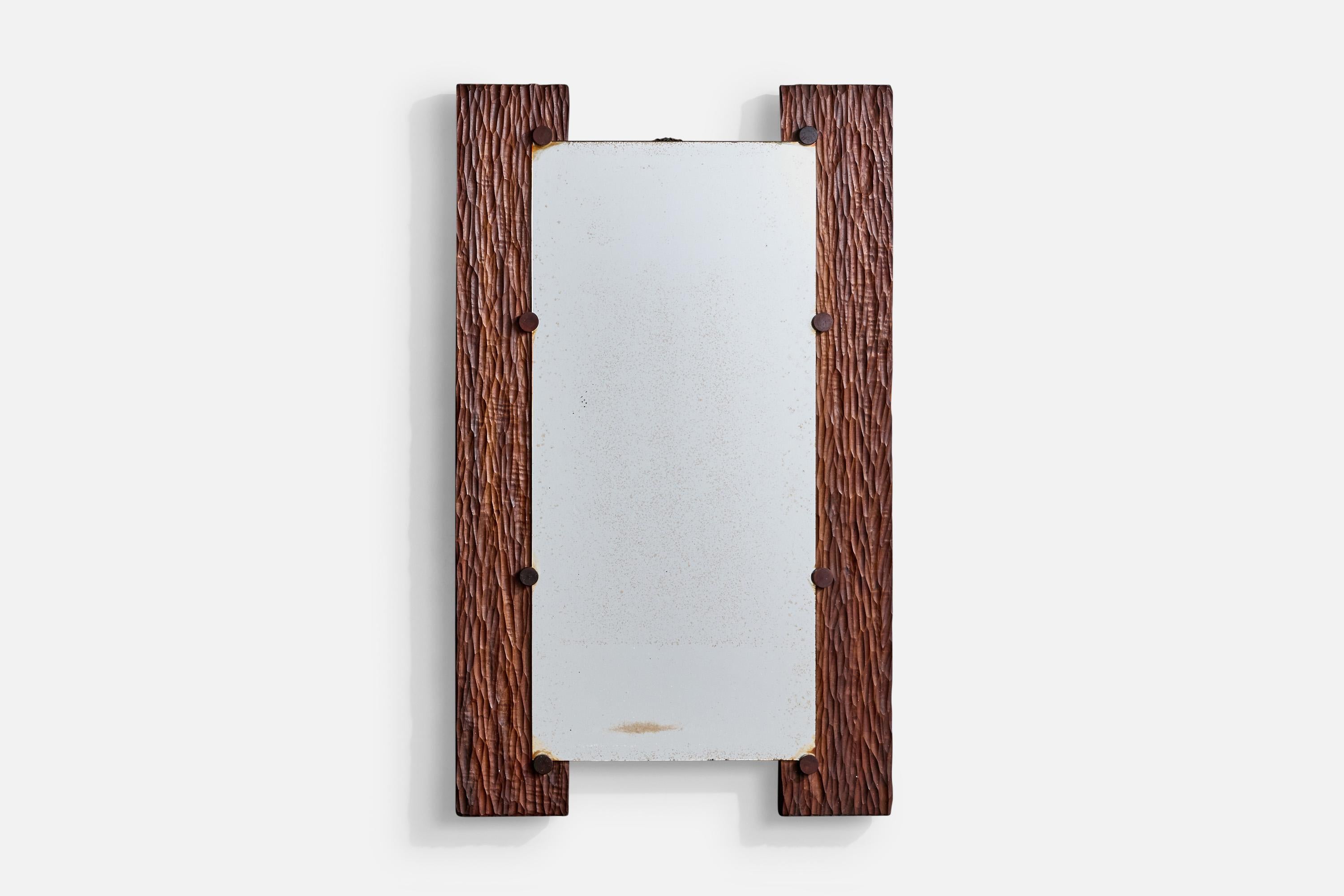 A hand-carved Gonçalo Alves wood and brass wall mirror designed and produced in Brazil, c. 1970s.

The mirror glass presents with light to moderate discoloration.

Dimensions: 41.125” H x 24.55” W x 2” D