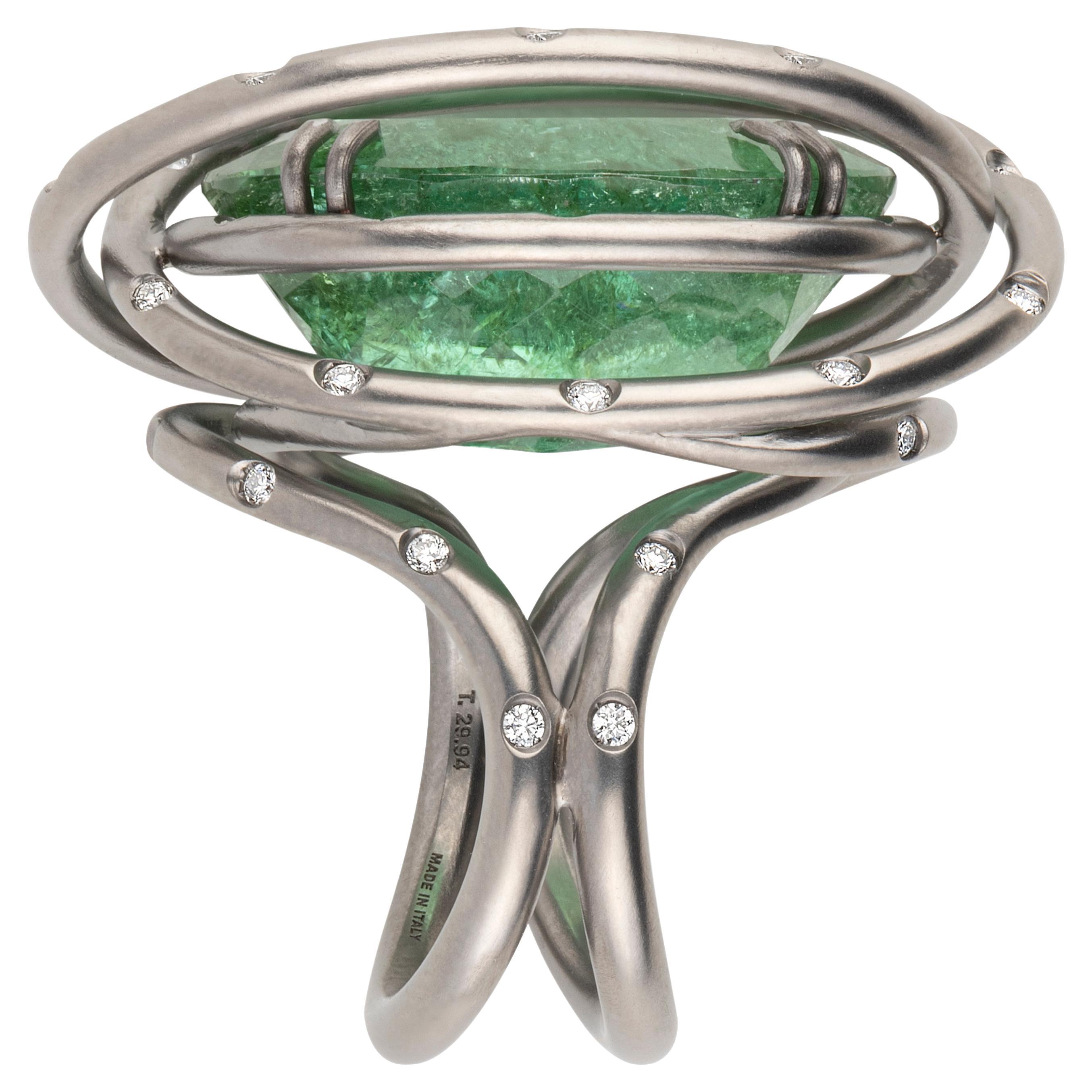 A  titanium wire is sculptured all around  the impressive and unique 9.94 carats Brazilian green  tourmaline  featuring several interesting inclusions, an enchanting 'jardin'. 
44 diamonds set on the wires are the bling bling touch.

n. 44 natural