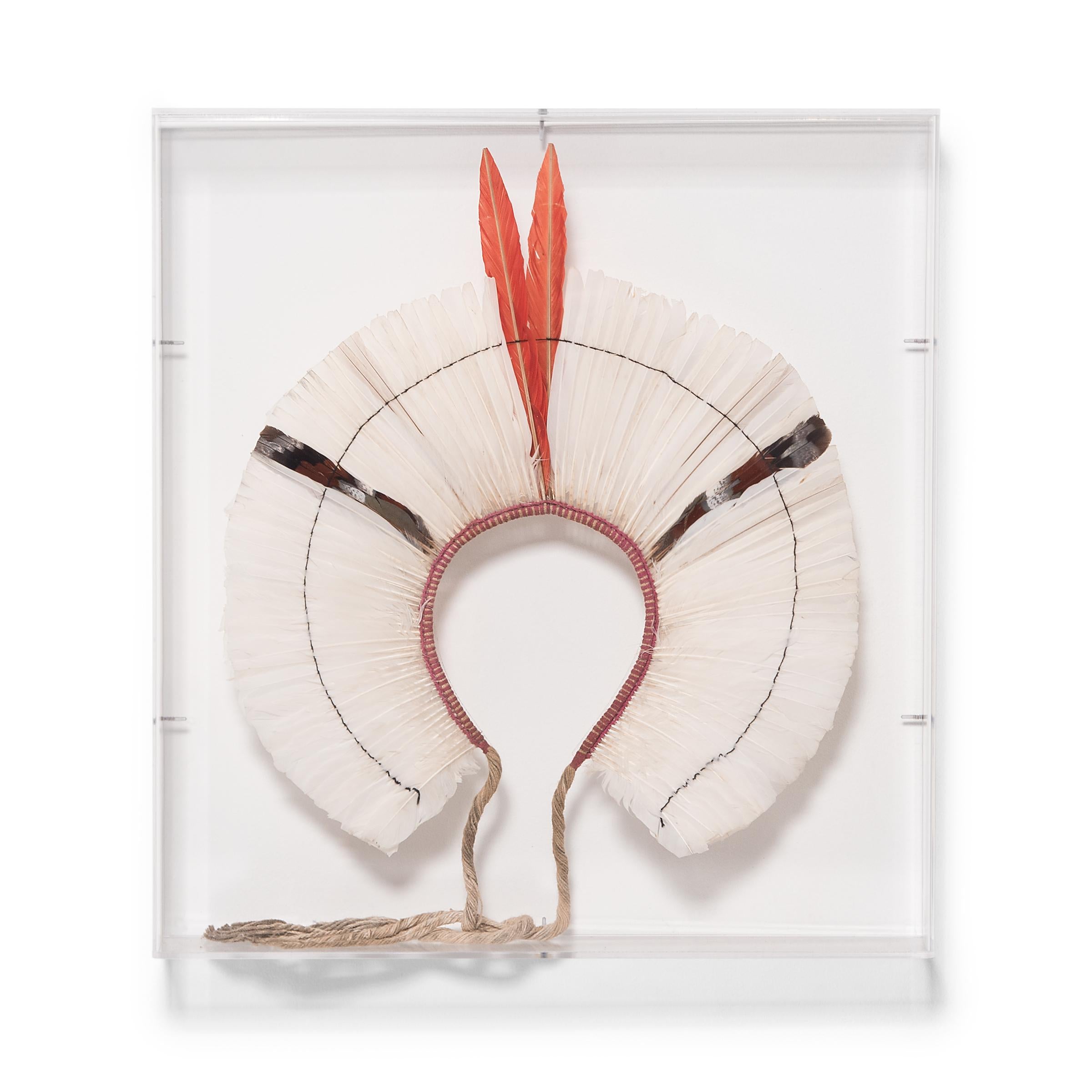 A breathtaking display of color and texture, this round feather headdress is a ceremonial headpiece of the Kayapo people, an indigenous group of the Amazon basin. Sourced from native birds with vibrant plumage, the fan of feathers radiates outwards