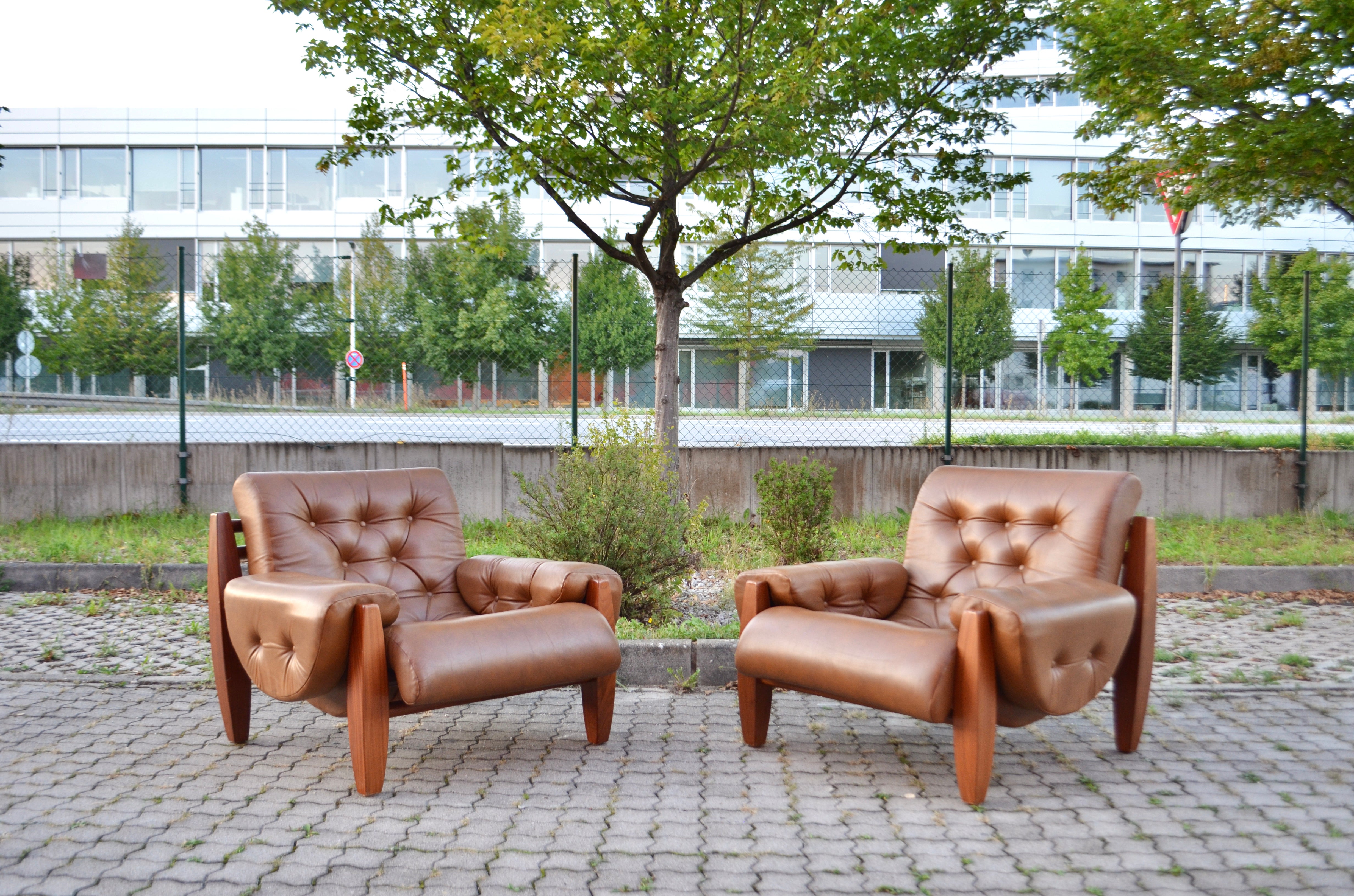 Dieser große Lounge-Sessel stammt aus den 1970er Jahren.
Er ist aus Pau-Ferro-Holz und cognacfarbenem Anilinleder gefertigt.
Unter dem Kissen befinden sich Riemen aus Sattelleder.
Das Design verweist auf die Arbeit von Jean Gillon, aber die