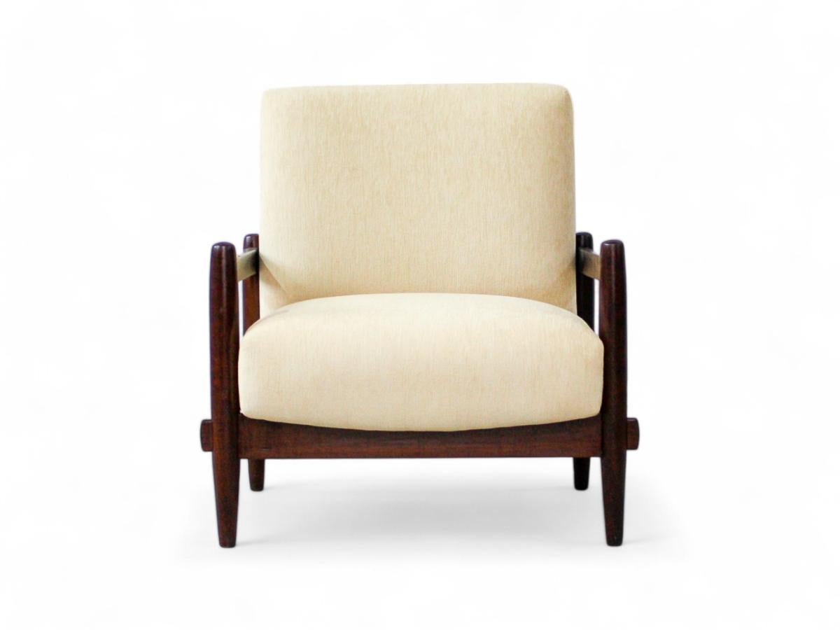 Crafted in the 1960s, this beautiful armchair features an Imbuia wood frame complemented by newly upholstered beige linen seat and backrest. The seat and backrest provide ample support, ensuring superb comfort. The wood has been meticulously