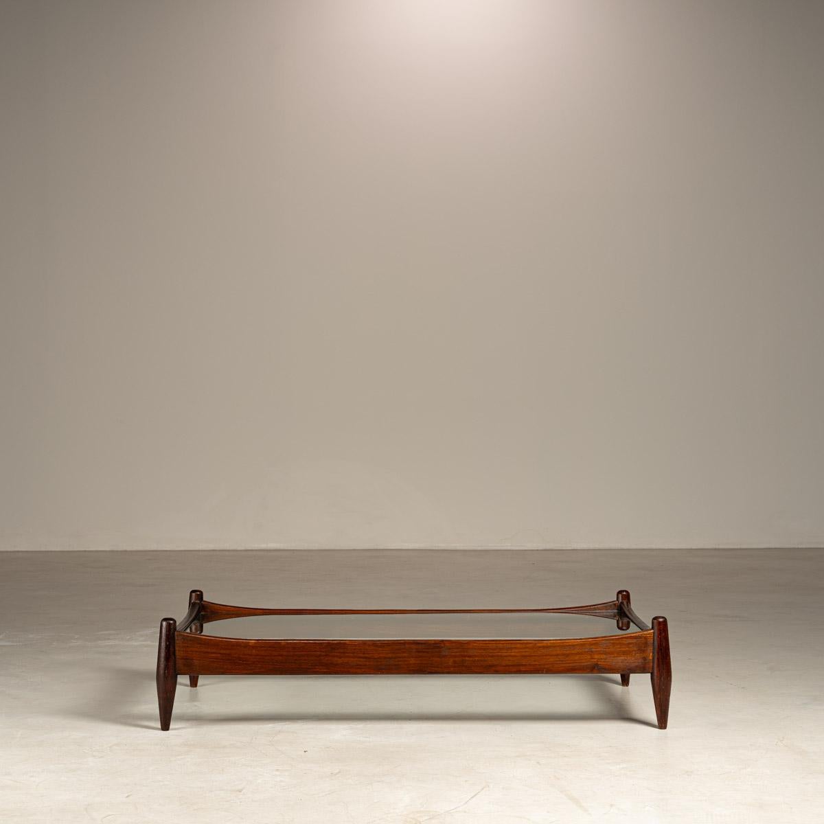 Questo splendido tavolino modernista brasiliano, attribuito al rinomato Liceu de Artes e Ofícios, incarna la raffinata maestria e l'estetica senza tempo del design degli anni Cinquanta. Realizzato in legno massiccio con un elegante piano in vetro,
