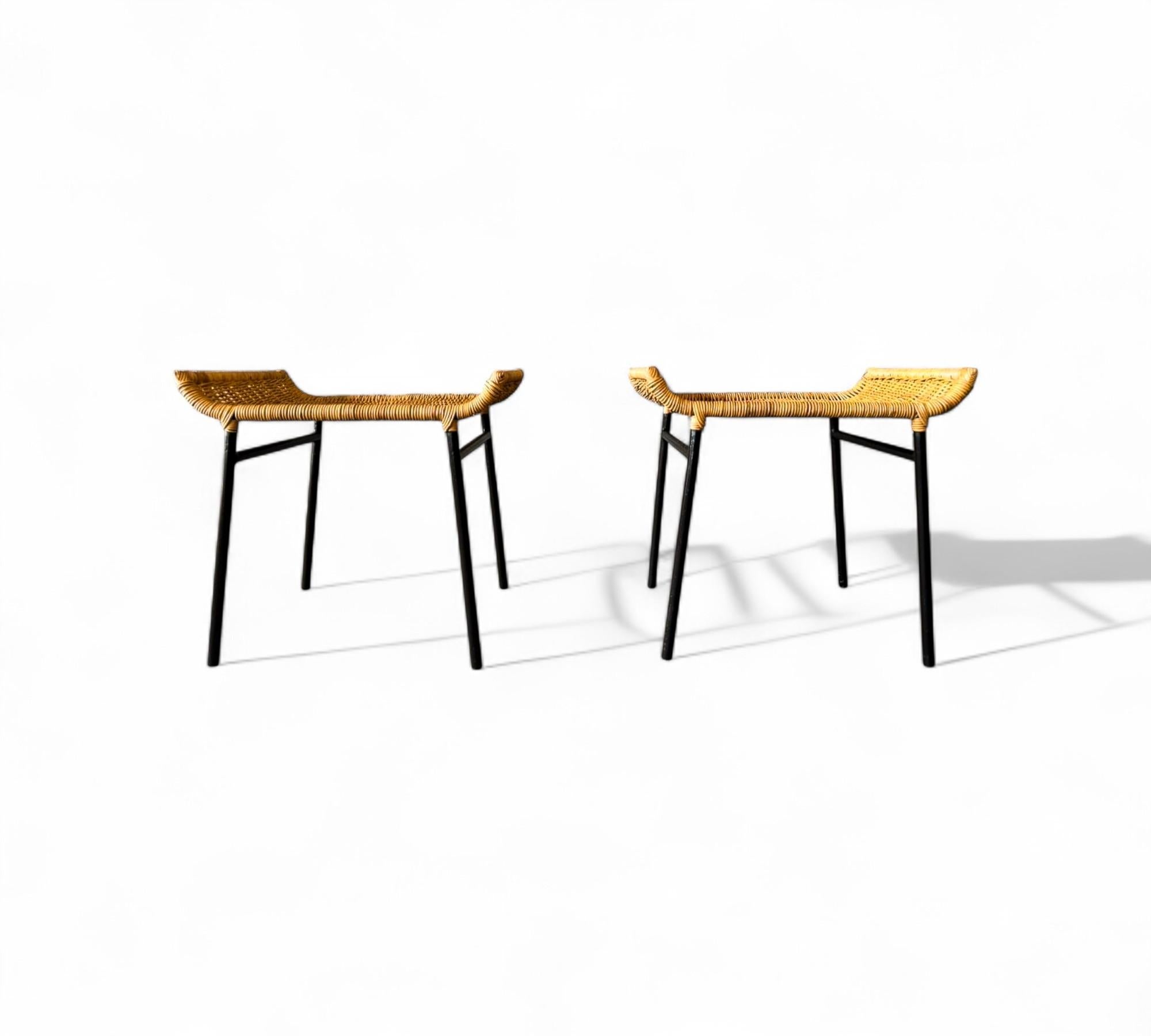 Diese Hocker zeichnen sich durch ihre elegante Schlichtheit aus. Sie haben eine handgeflochtene Sitzfläche aus Schilfrohr, die an den Rändern anmutig geschwungen ist und von schlanken schwarzen Eisenbeinen getragen wird, die ein auffallendes