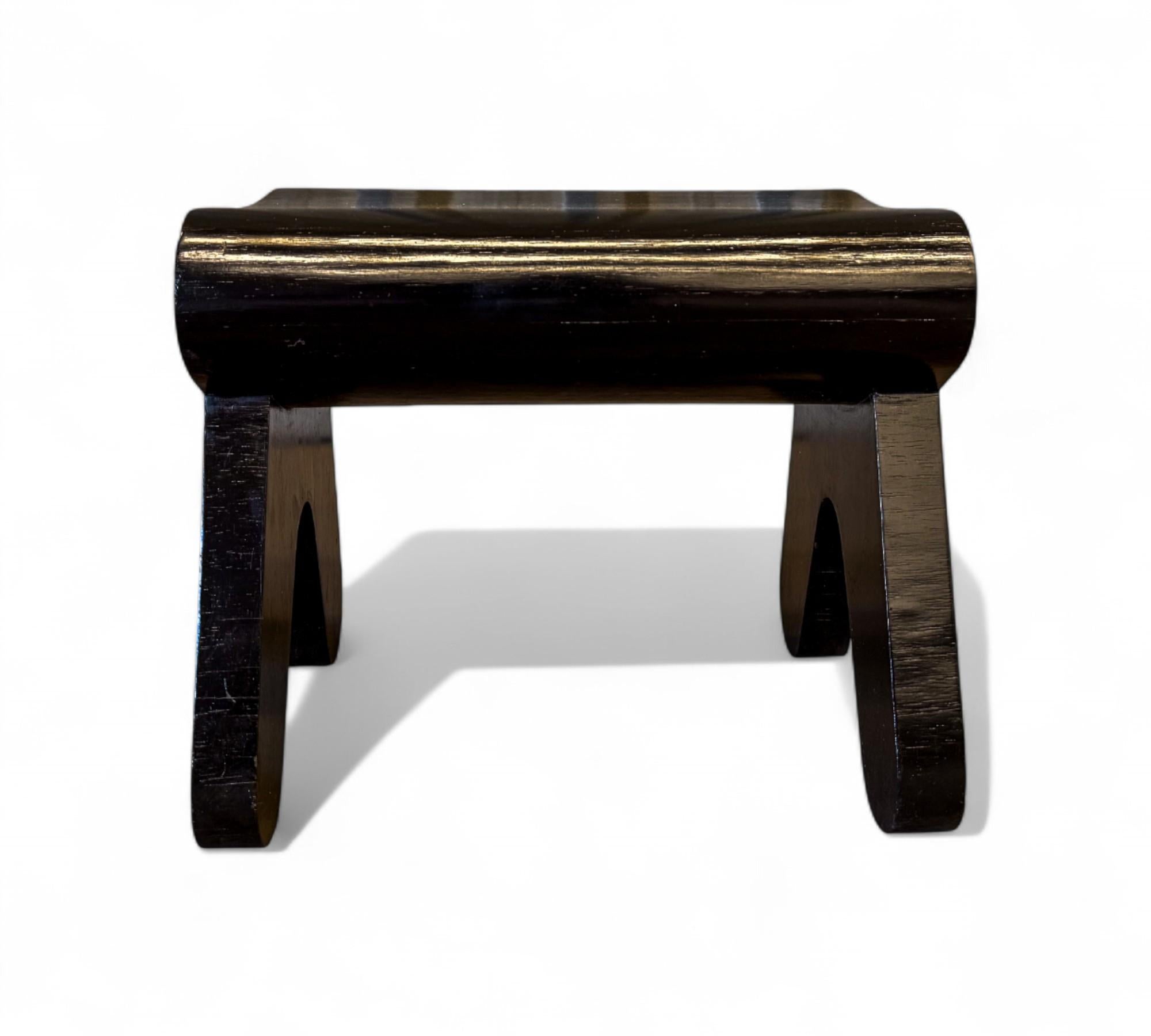 Este escultural taburete del diseñador brasileño Pedro Useche muestra su característica mezcla de forma lúdica, claridad arquitectónica y refinada artesanía. Construida en madera maciza de tonos contrastados, la pieza presenta un asiento redondeado