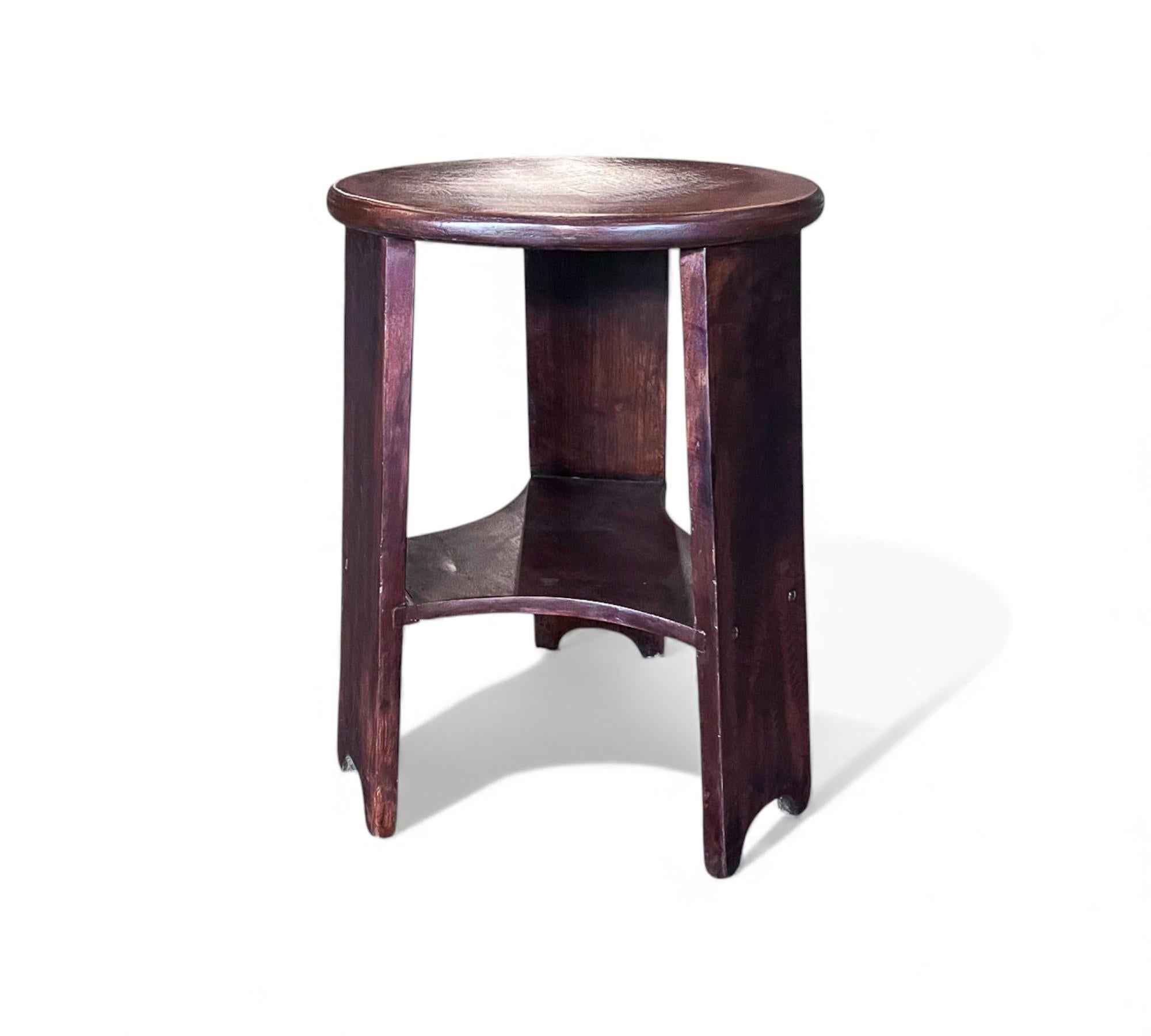 Este taburete de madera dura de Cimo Móveis está construido con un sólido tablero redondeado y tres patas suavemente curvadas, la pieza tiene una forma robusta y equilibrada adecuada para el uso diario. Un estante de conexión inferior añade soporte