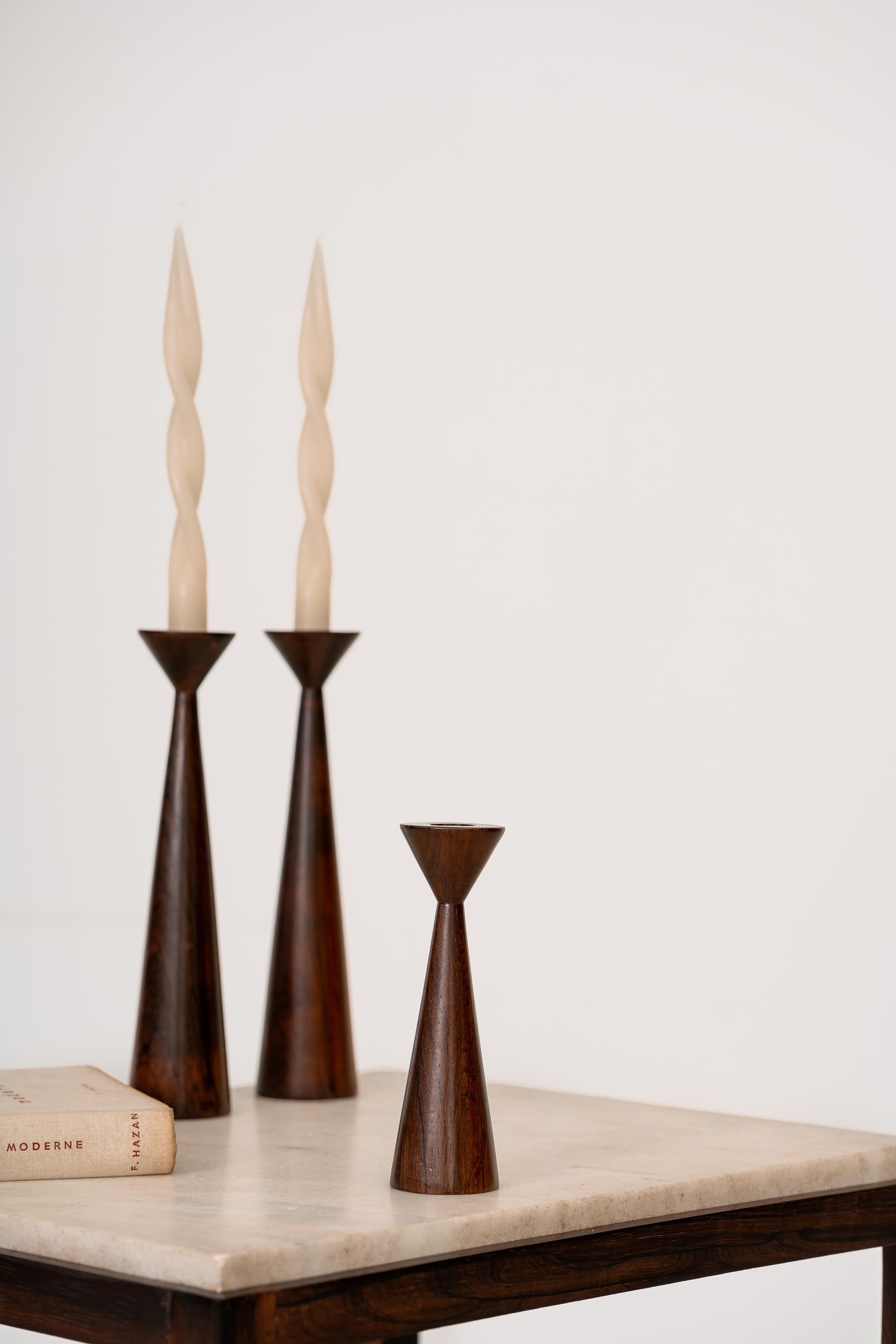 Stunning mid-century candlestick made in solid Brazilian rosewood of unknown authorship. It is the shortest in the group.