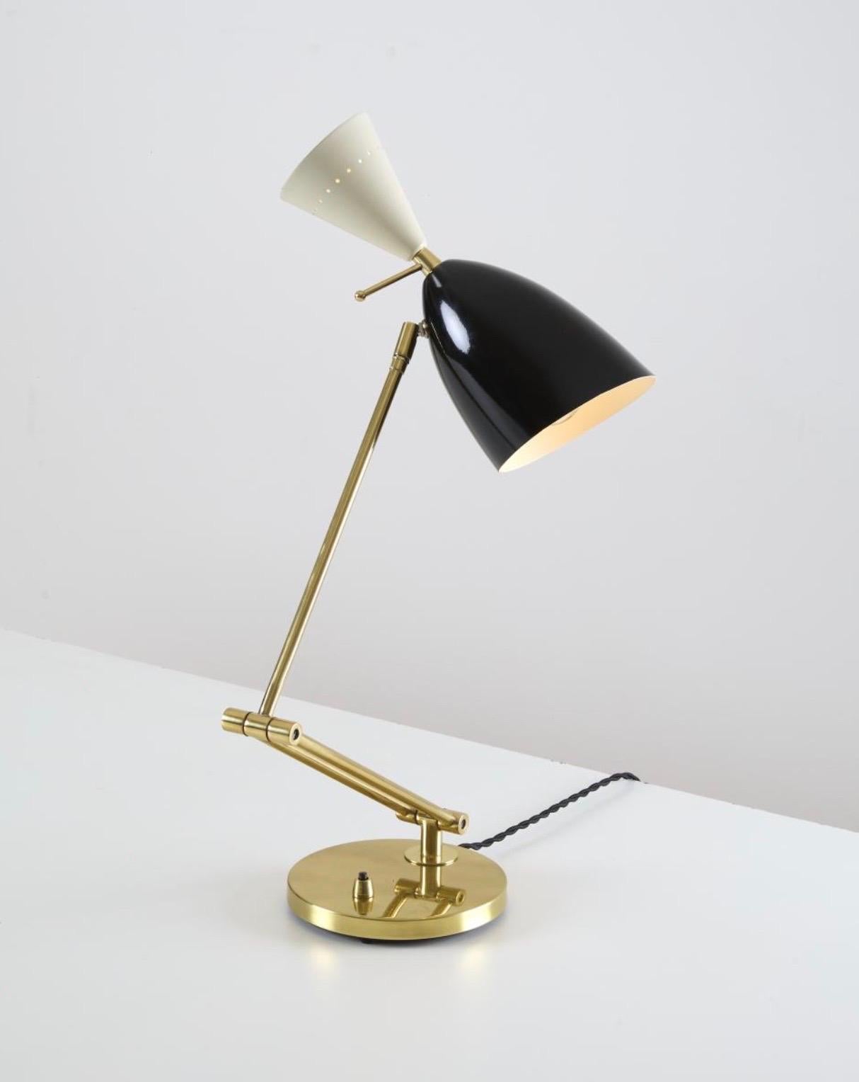 Una sorprendente lampada da tavolo brasiliana della metà del secolo scorso, realizzata in ottone lucido con un doppio braccio articolato che poggia su una base circolare. Il paralume conico regolabile, realizzato in alluminio smaltato nei colori