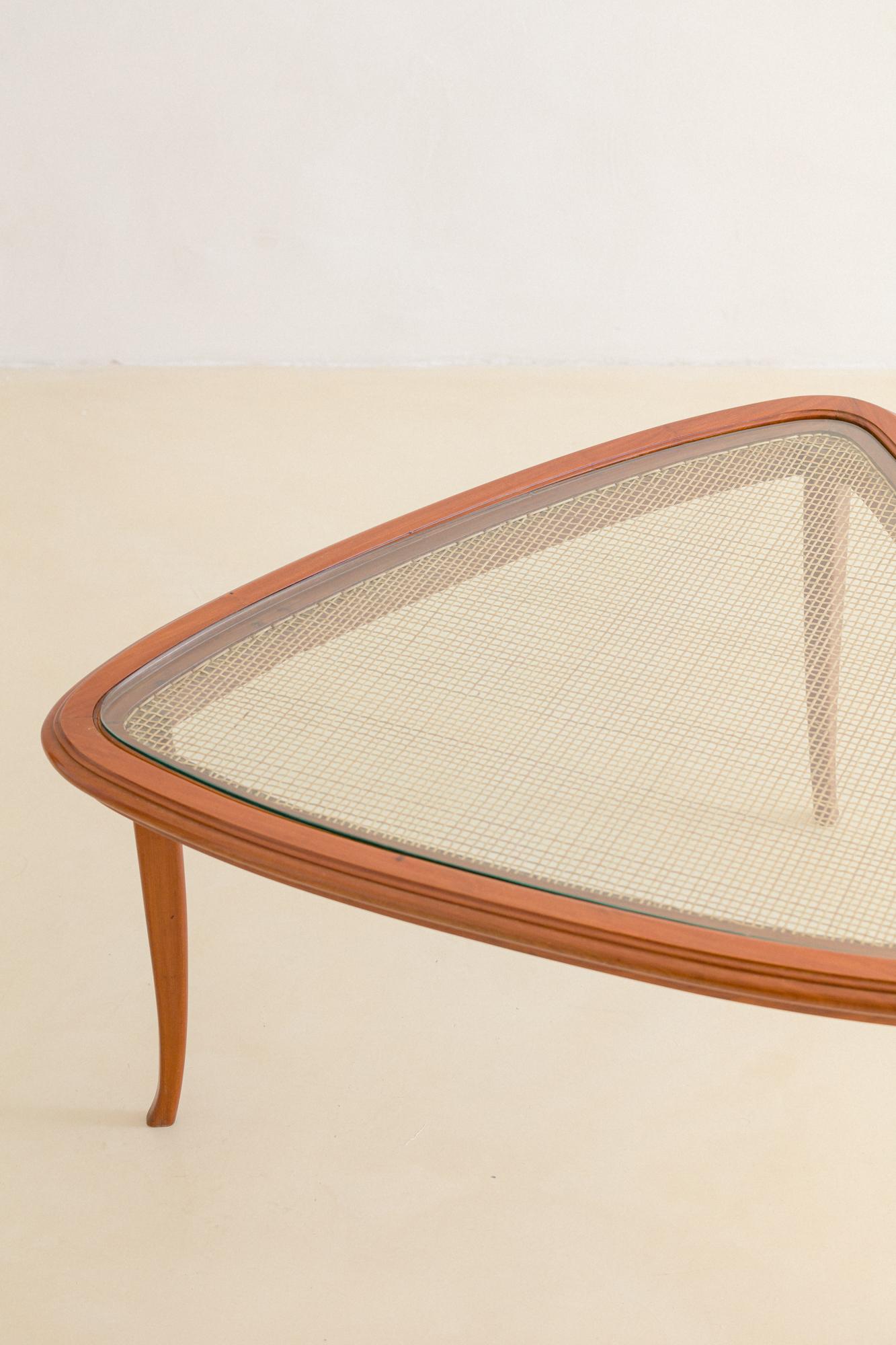 This charming Triangular coffee table was designed in the 1950s. 

The three-leg table is composed of a solid Caviuna structure and has rounded corners. The table's top is made of glass, but its biggest highlight is a weave of natural cane,