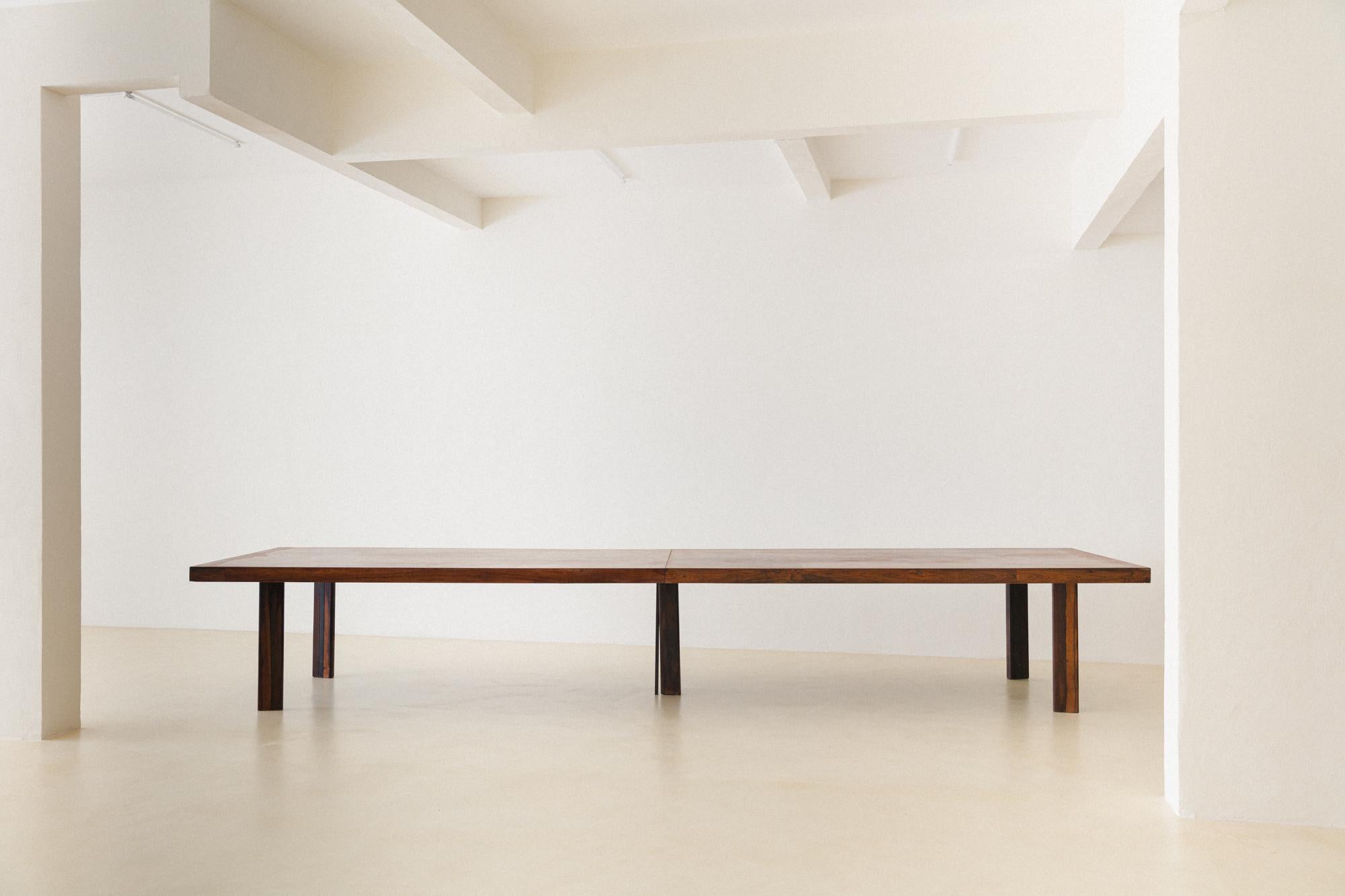 This long dining table was manufactured in the 1960s, but its authorship is still in research. The piece is made of solid Rosewood and Rosewood veneers, and its structure is composed of four parts: two parts for the base and two parts for the top.
