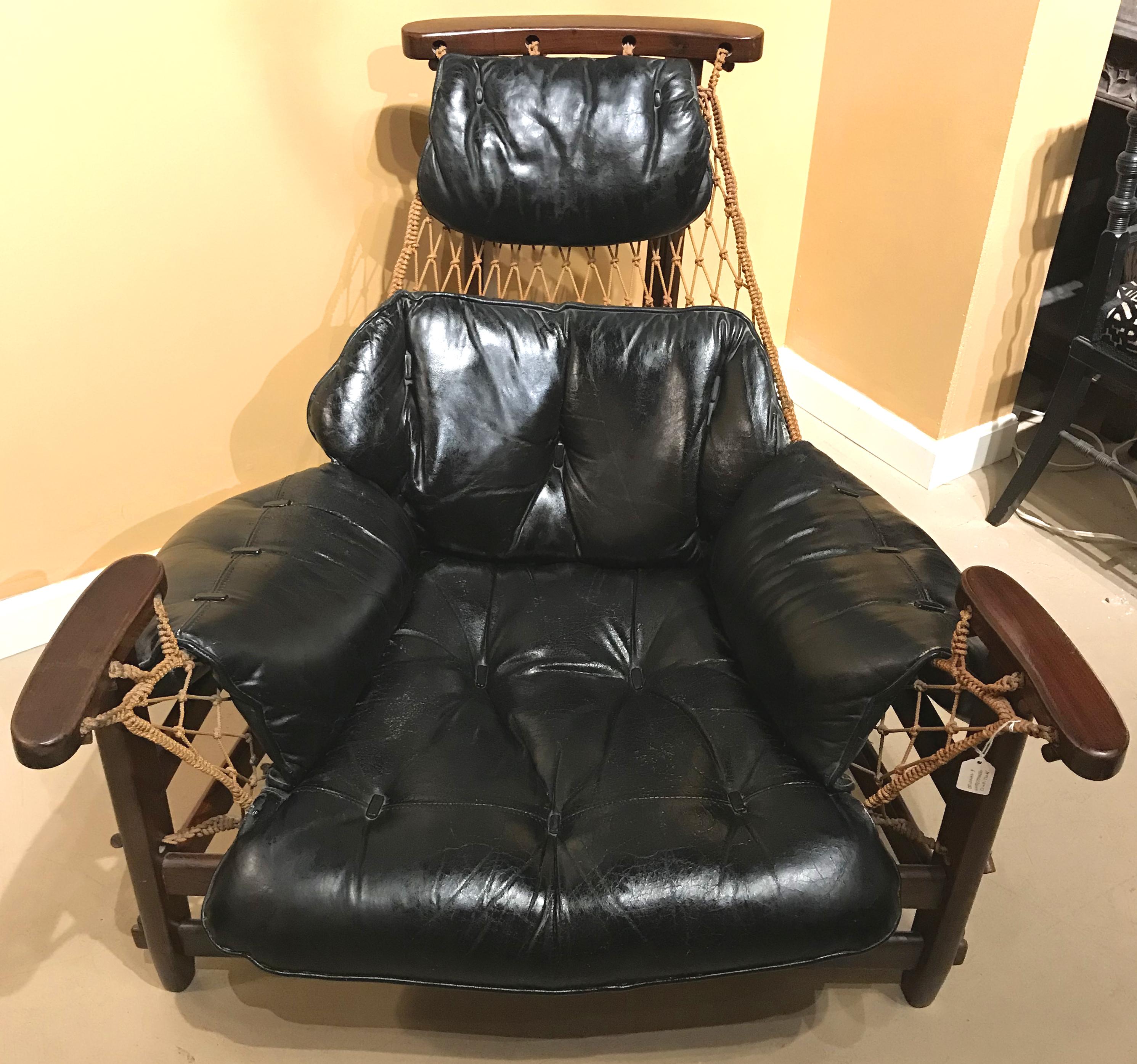 A fabulous Brazilian midcentury gran captain or “Jangada” lounge chair in jacaranda wood with distressed black tufted leather seat in woven rope sling designed by Jean Gillon and produced by Italma Wood Art, circa 1960. An Italma Wood Art label