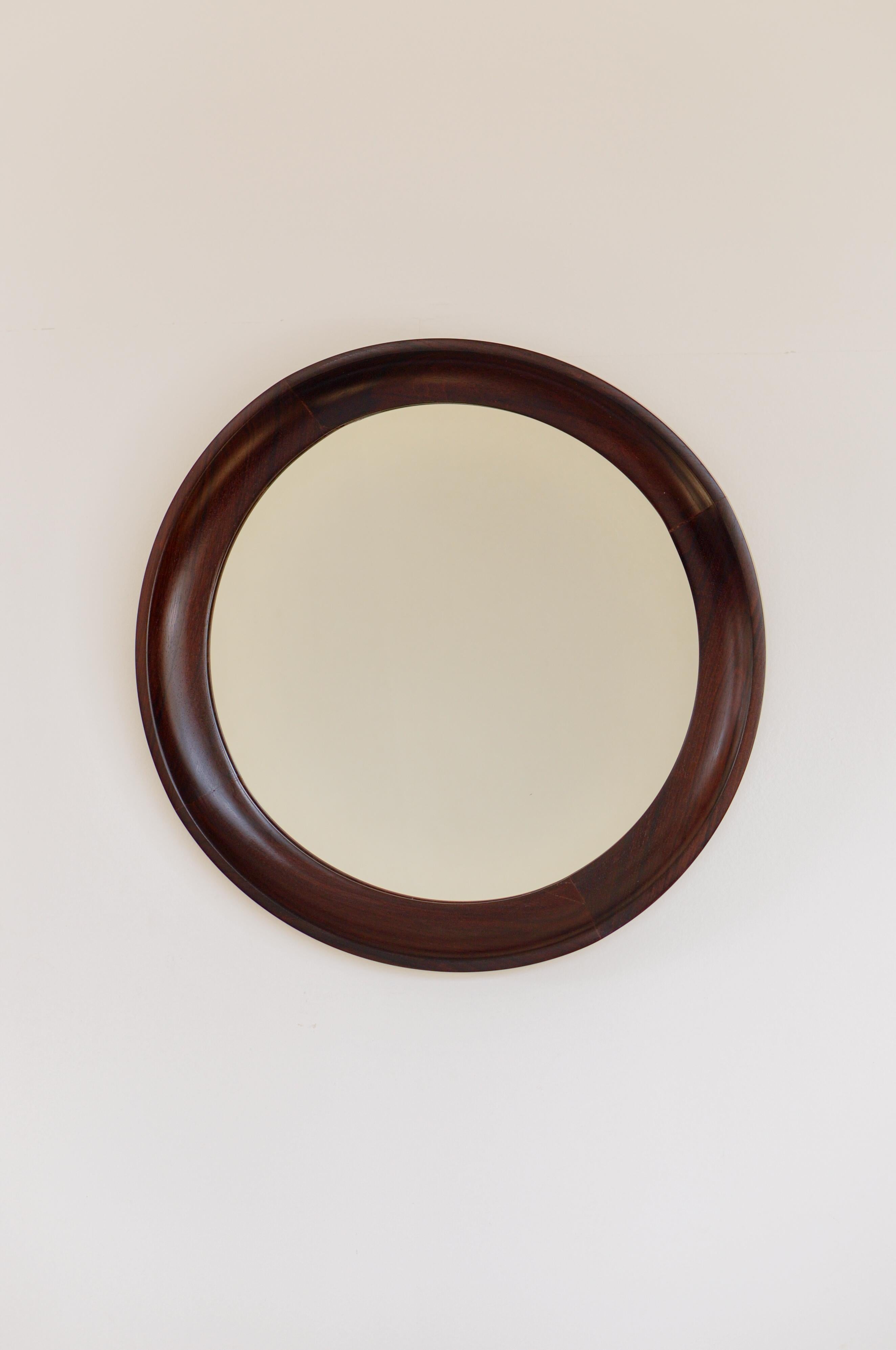 Round mirror with Brazilian rosewood frame. It retains the seal of 