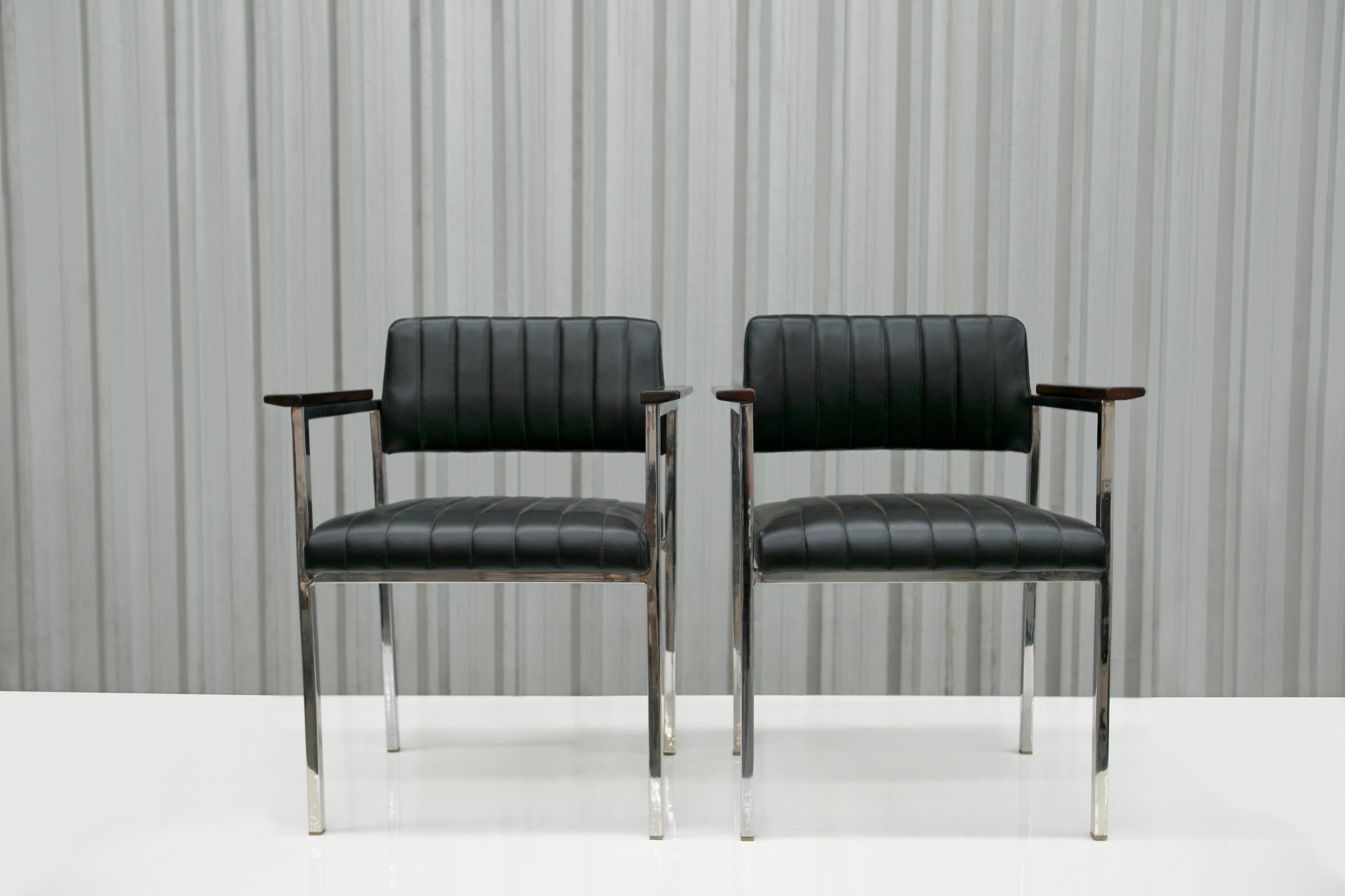 Disponibles aujourd'hui, ces fauteuils modernes brésiliens en acier, cuir et bois inconnus, années 1960, Brésil, sont magnifiques. 

La structure de ces chaises est en acier et l'assise et le dossier sont en cuir noir. En outre, les accoudoirs sont