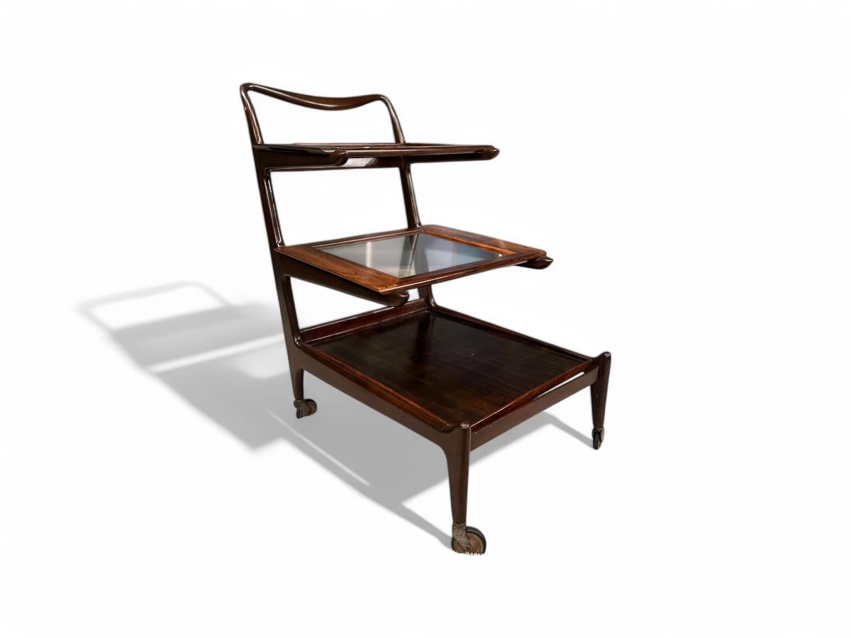 Designed by Carlo Hauner and Martin Eisler for Forma S/A Móveis e Objetos de Arte, the bar cart is made of Brazilian Rosewood (Jacaranda), glass, and steel. Composed of three removable serving trays, this piece is in excellent condition. The wood