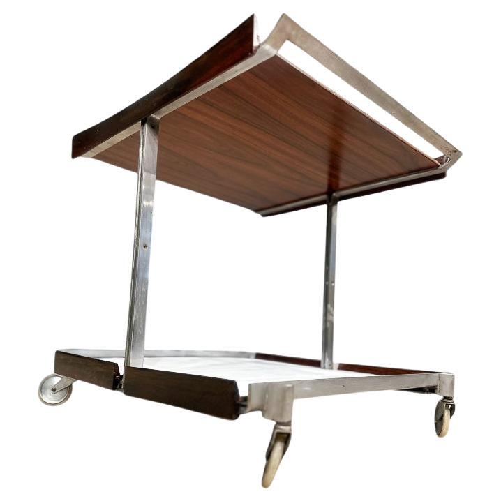 Presentamos un impresionante carrito de bar que combina a la perfección estilo y funcionalidad. Esta exquisita pieza cuenta con un elegante armazón cromado, elegantemente complementado con dos bandejas extraíbles. Uno de los lados de cada bandeja