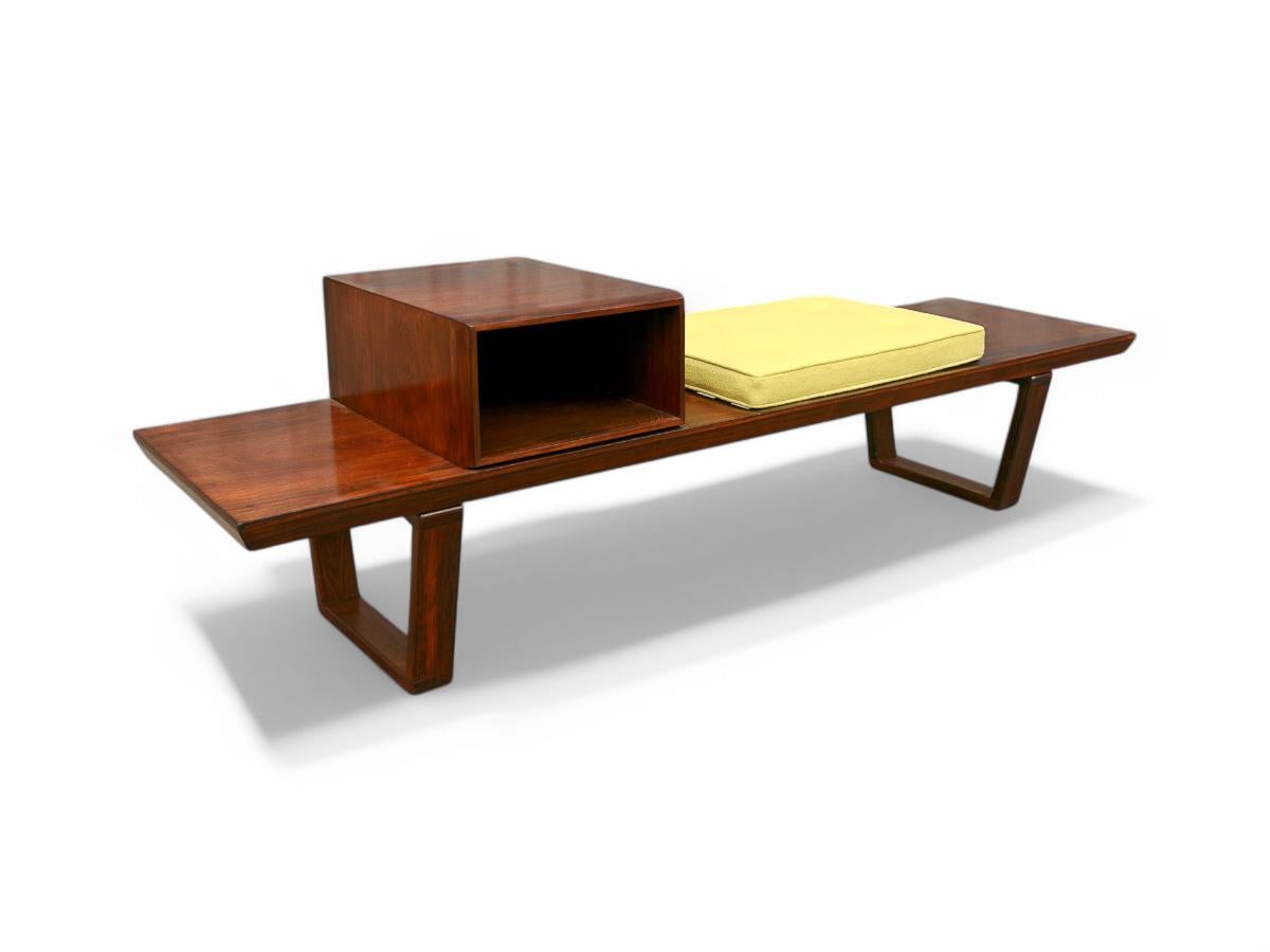 The bench features two legs, a module for storage and one seat with a reupholstered yellow fabric. The piece is made with Brazilian hardwood and it has a beautiful color and pattern to it. The wood has also been refinished and is in excellent
