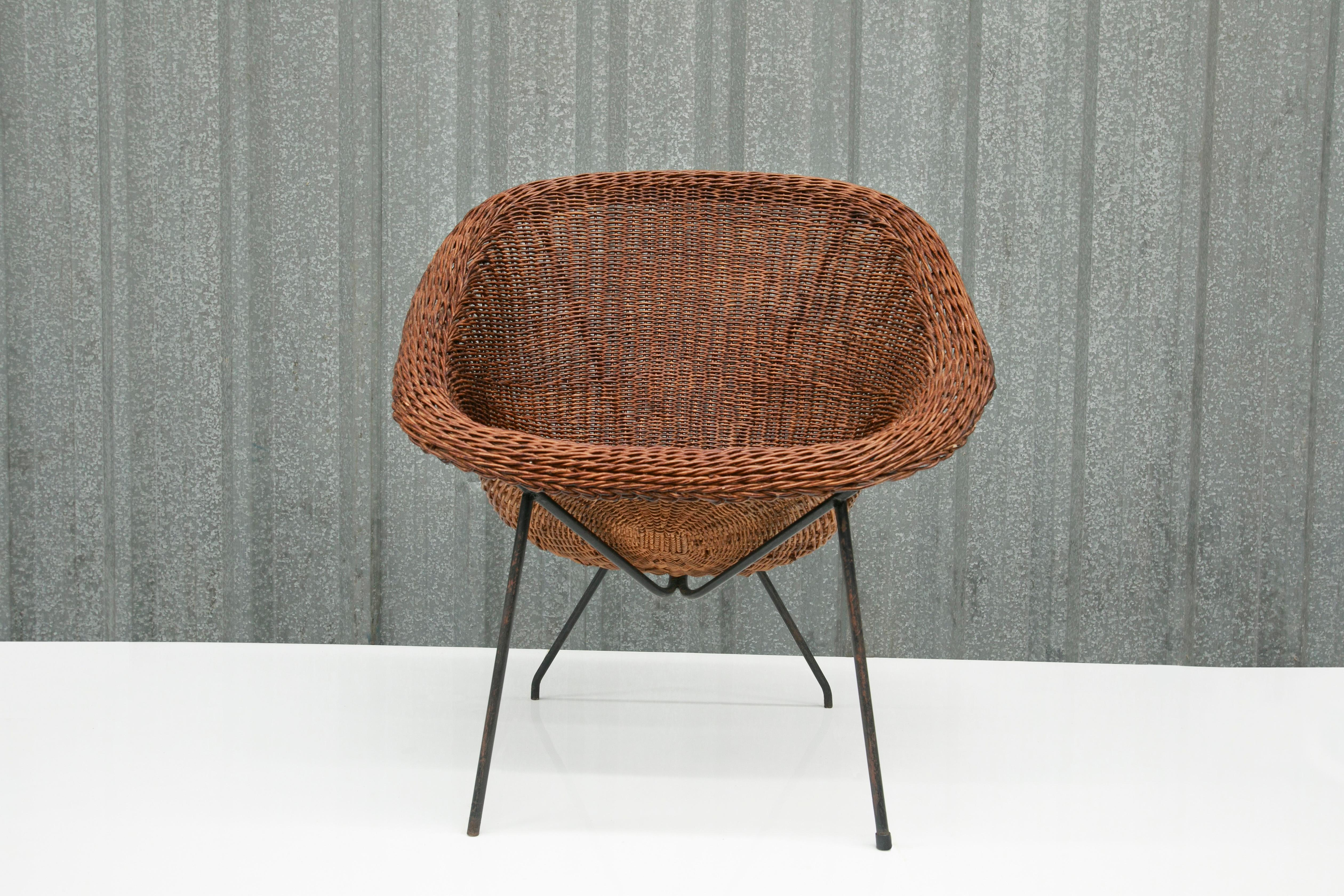 This Brazilian modern chair was designed by Carlo Hauner & Martin Eisler in 1955. The frame is made with a black iron structure that supports the cane seating. The seat of the chair is curved and sinks in, which allows for a super comfortable