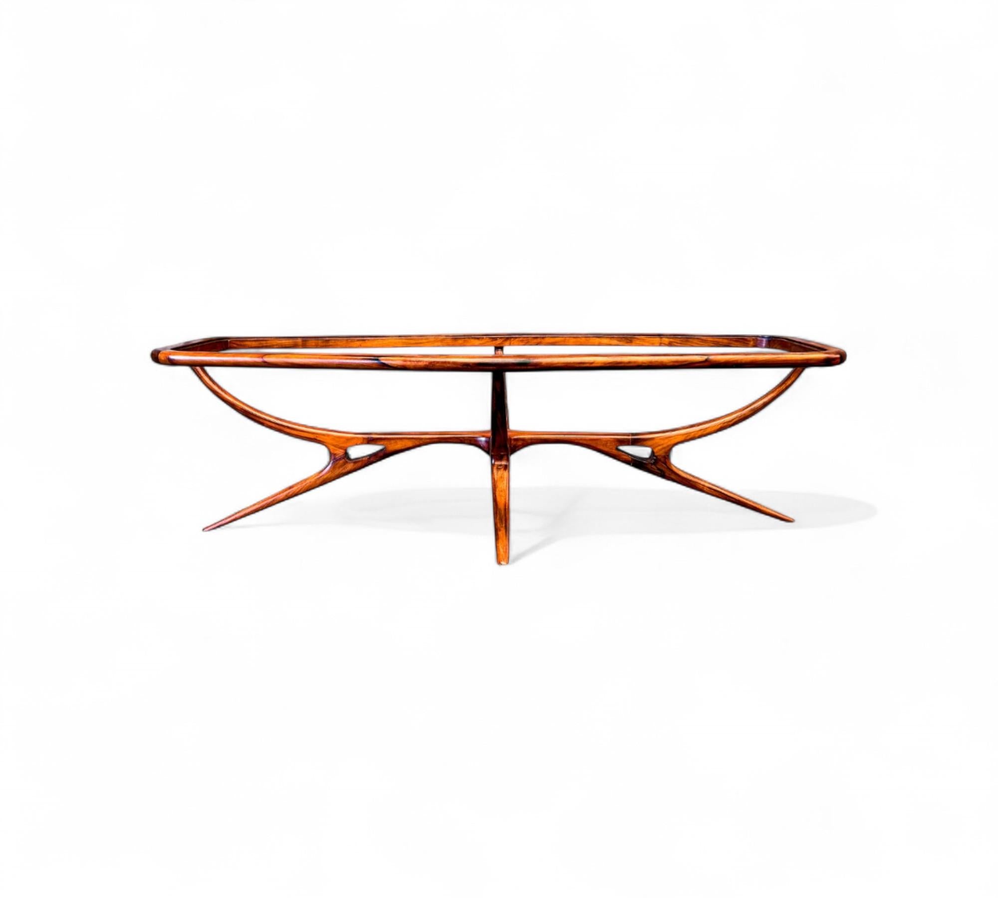 Cette table basse est dotée d'un cadre en bois dur Caviuna, d'un plateau en verre et de quatre pieds. La table a la forme d'un ovale et le bois présente un beau motif. La forme de la table et le style des pieds sont ce qui rend cette pièce si unique