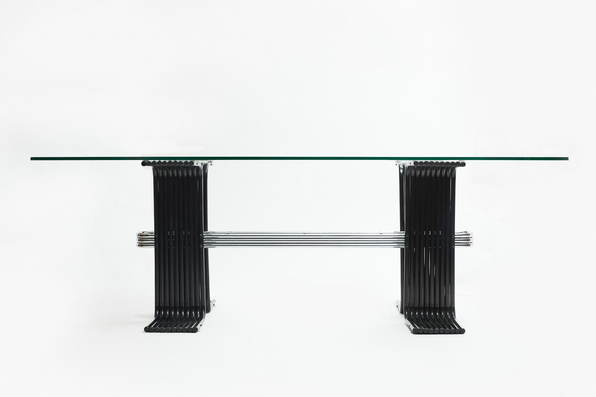 This mid-century modern dining table, designed by Forma in the 1970s in Brazil, is available today. Painted in black iron, with chromed metal accents and a 10 mm glass top, it is nothing less than spectacular.

The monumental table has two large