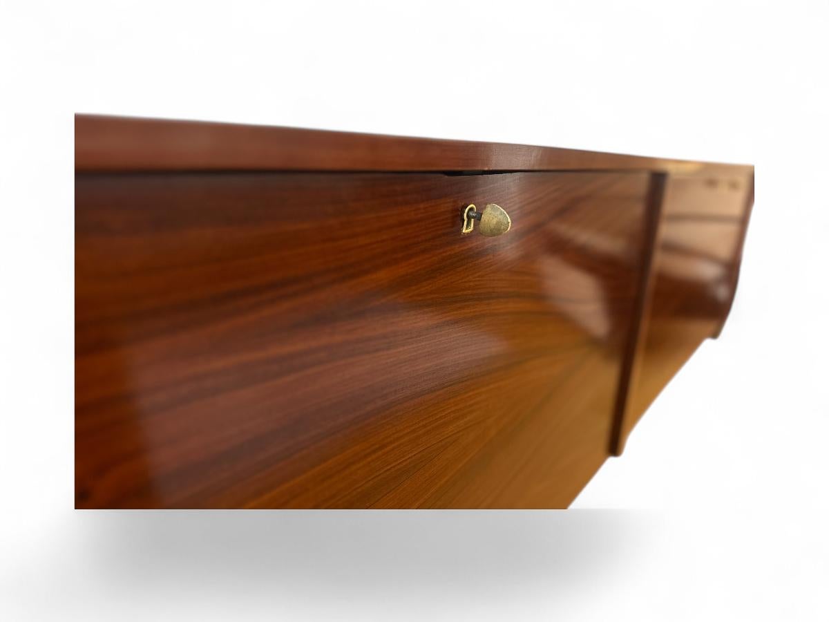 Questa elegante credenza (o bar) galleggiante, realizzata in legno di palissandro e disegnata da Carlo Hauner per Forma negli anni '60, presenta un'elegante silhouette rettangolare. È dotato di due ante e quattro scomparti interni con ripiani in
