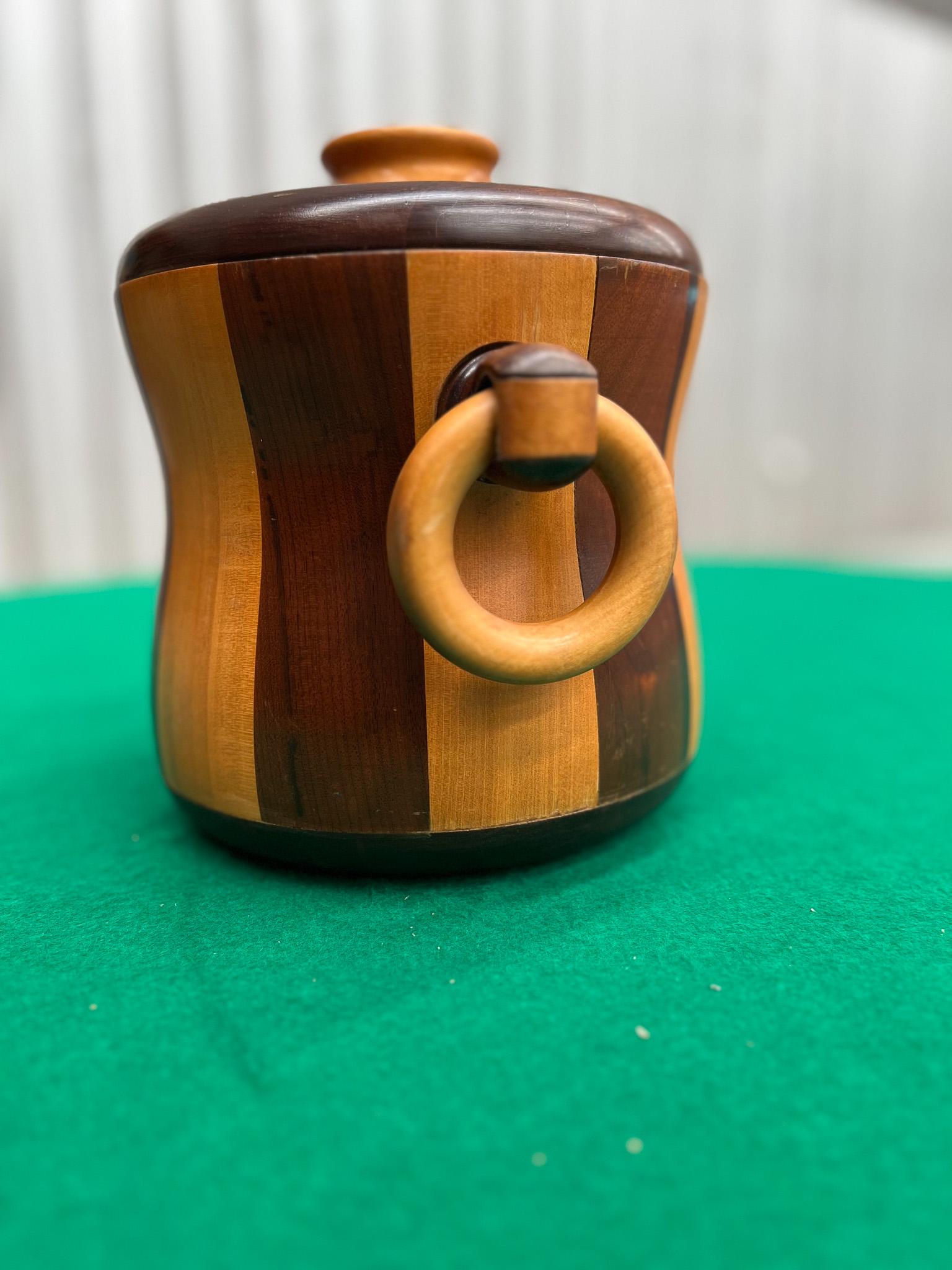 Available today, this mid-century modern ice bucket that was made in the sixties is one of a kind! This beautiful wooden ice bucket is made with imbuia hardwood and Brazilian rosewood (also known as Jacaranda), and has two rounded handles on the