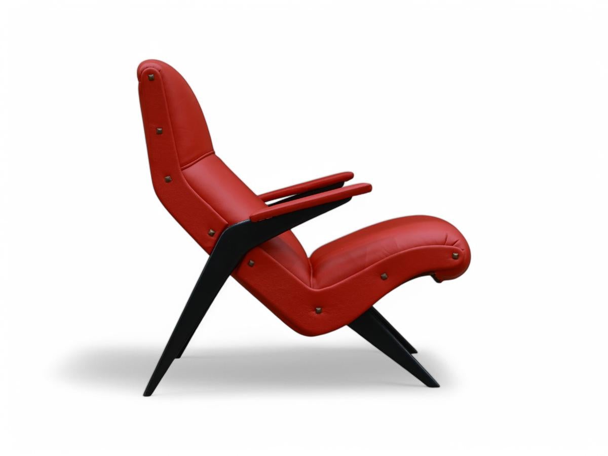 Ce fauteuil éclectique est fabriqué en bois dur ivoire (Pau Marfim) avec une élégante finition ébène et orné d'un revêtement en cuir rouge vibrant. La chaise est dotée d'une assise et d'un dossier moelleux ainsi que de deux accoudoirs, ce qui