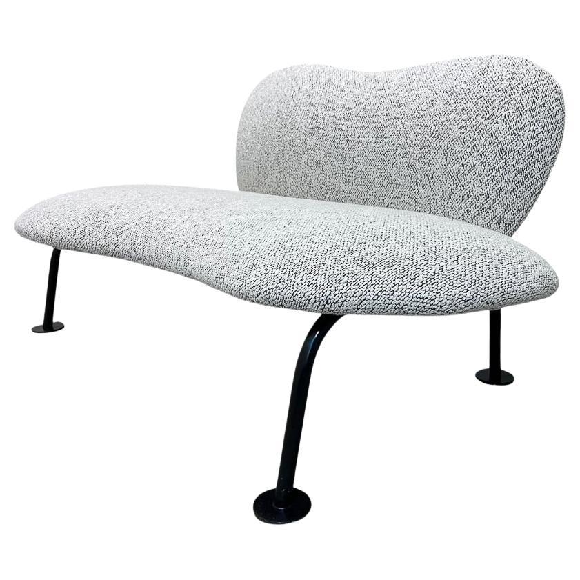 Este pequeño loveseat de aspecto curioso y divertido tiene una estructura de madera de Freijo, patas tubulares de metal pintado en negro y tapicería de cuero ecológico. Este tipo de forma orgánica formaba parte de la tendencia de diseño orgánico que