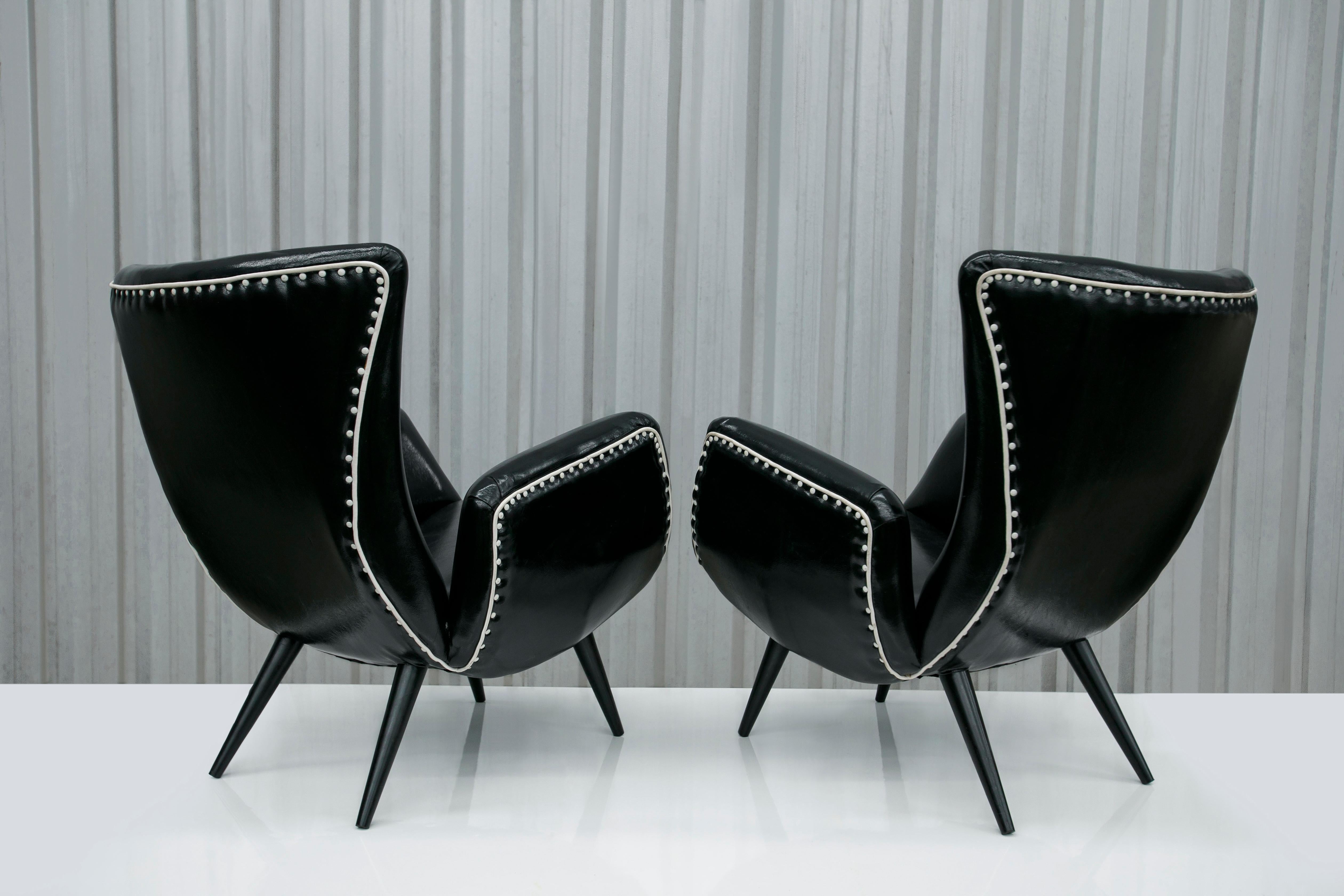 Disponible dès aujourd'hui, avec livraison nationale dans la région métropolitaine de New York incluse, cette paire de fauteuils modernes brésiliens en & faux cuir noir, A.I.C., vers les années 1950, n'est rien de moins que splendide !

Le cadre de