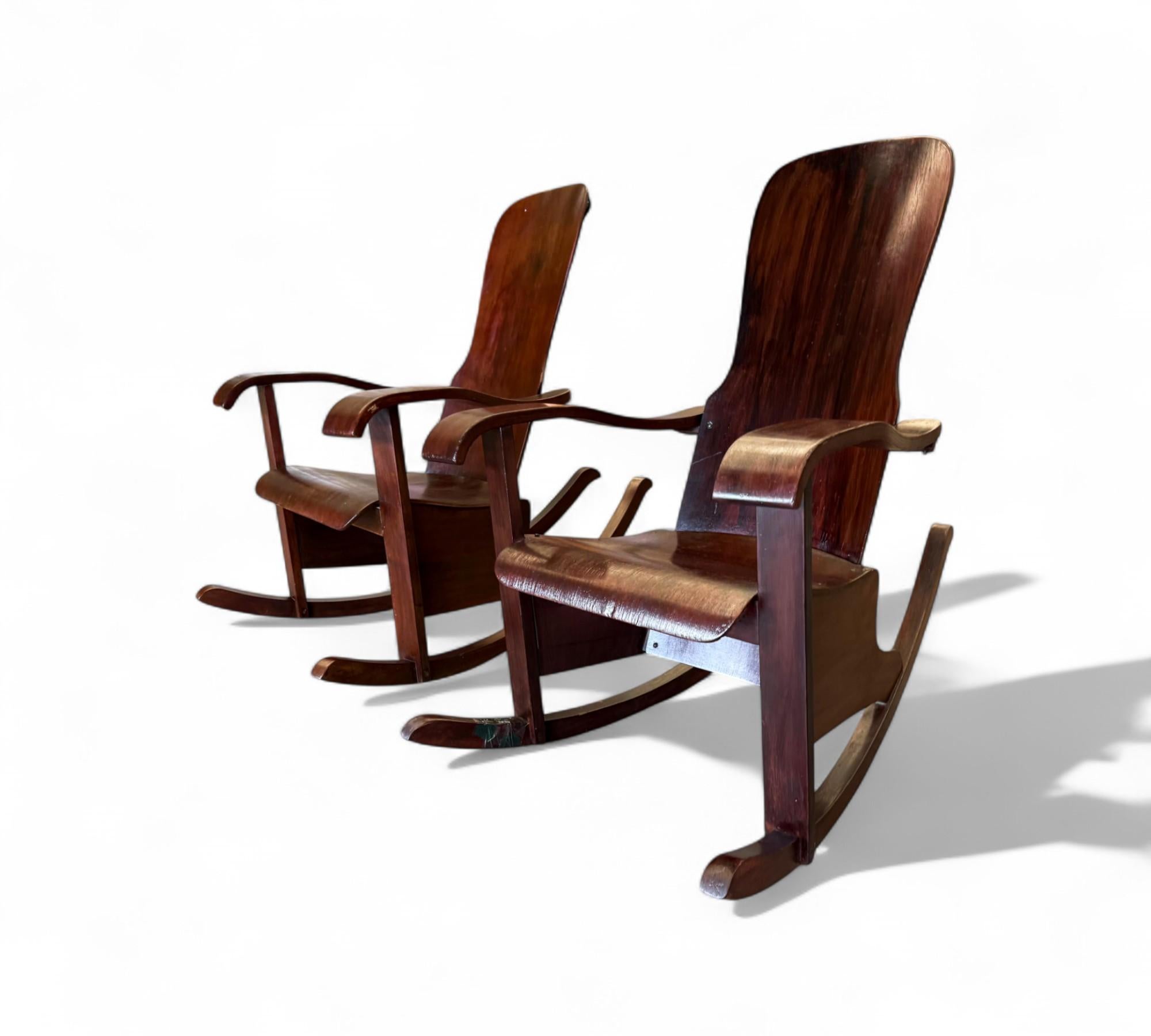 Estas excepcionales mecedoras, fabricadas por el célebre diseñador brasileño Cimo en la década de 1950, exhiben una exquisita forma escultórica totalmente construida con hermosa madera curvada. Cada silla tiene un respaldo alto y un asiento