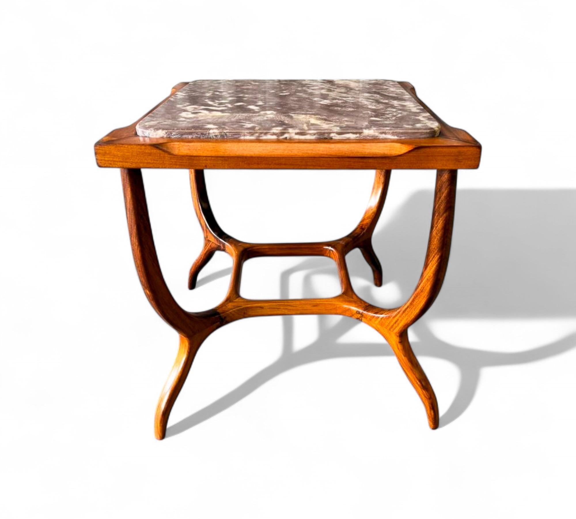 This sculptural mid-century side table showcases the elegance and craftsmanship of Brazilian design, featuring a solid Caviúna wood base paired with a striking purple marble top. The fluid, curved legs and central stretcher create a graceful,