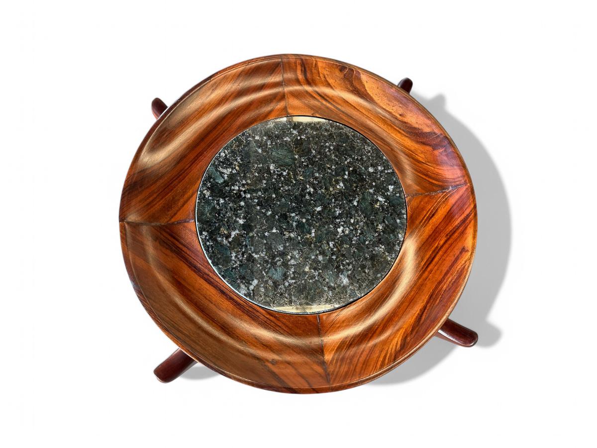 Disponible dès aujourd'hui, l'emblématique table basse Maracanã de Giuseppe Scapinelli est fabriquée en bois de Caviuna et en granit noir épuré. Le plateau est doté d'une base circulaire en bois qui accueille le marbre, ce qui lui confère un aspect