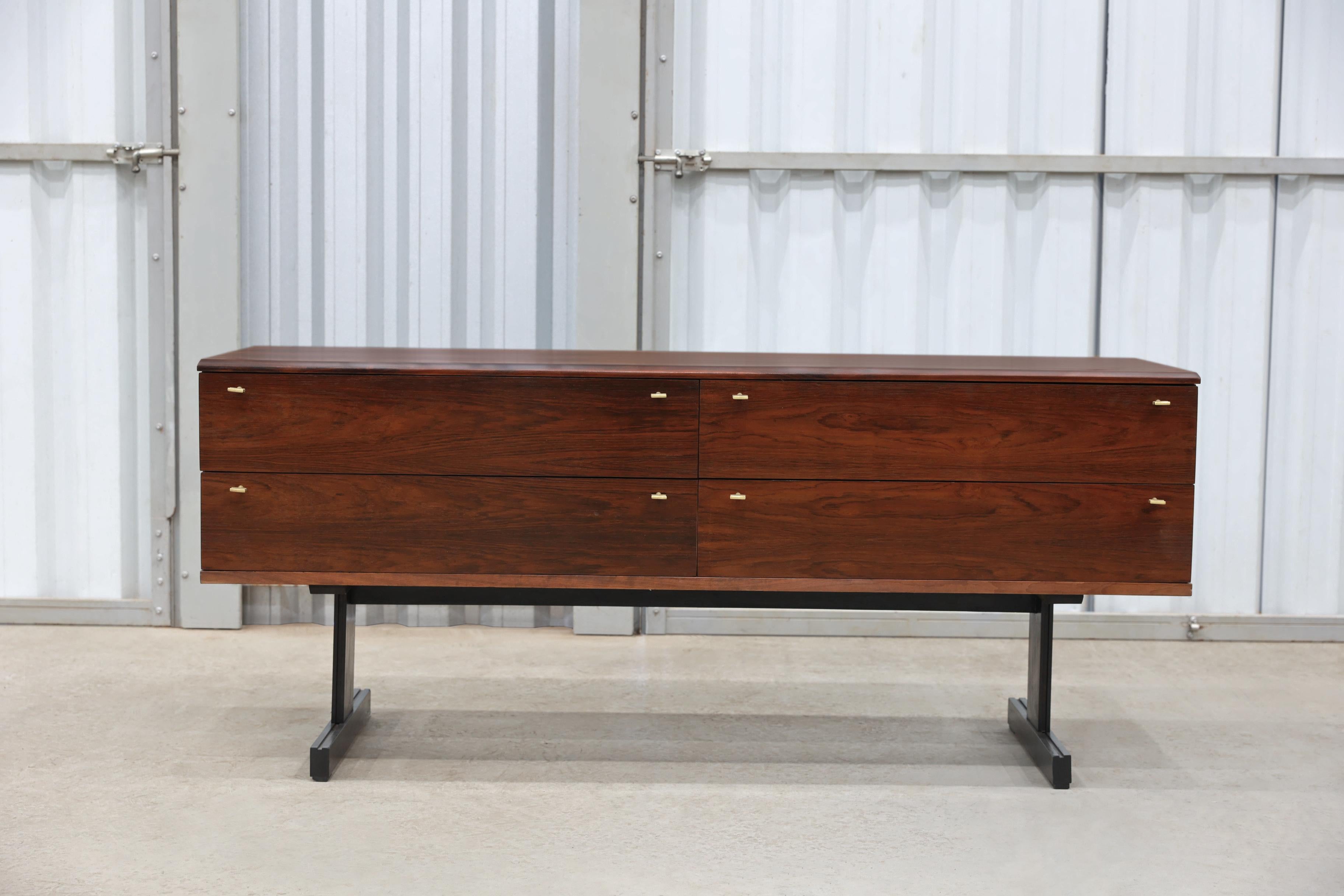 This sideboard designed by Cimo during the sixties in Brazil is made in Brazilian Rosewood, known as Jacaranda. The main structure has 4 large drawers with brass handles and it stands in two slim legs. The woodwork is excellent and the space is