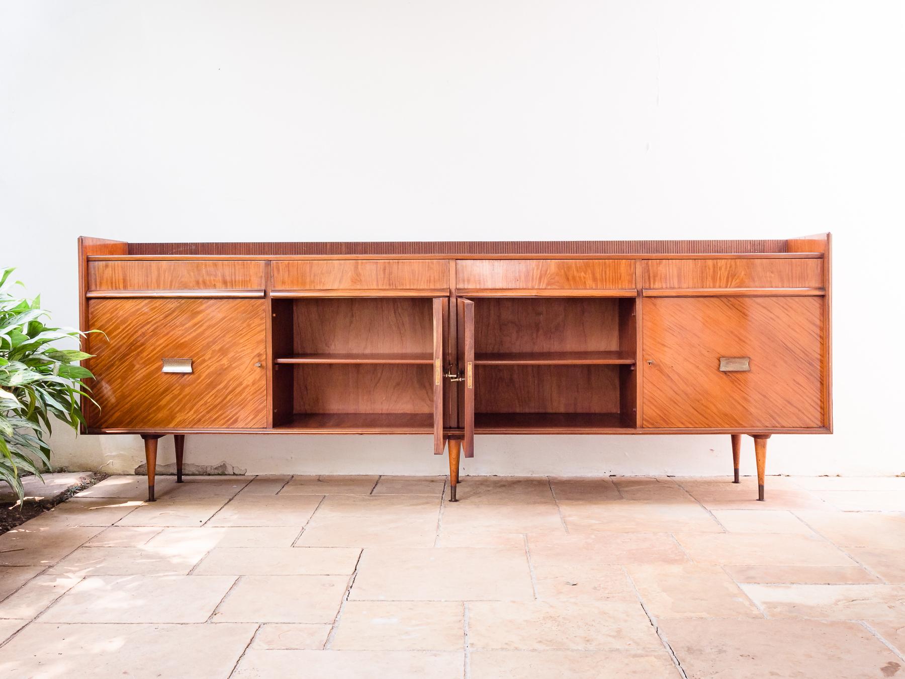 Brazilian Mid-Century Modern sideboard, in Caviúna hardwood, designed by Italian-born designer Giuseppe Scapinelli, circa 1955. Four doors and four drawers, brass feet.
This exquisite and big sideboard was designed by Giuseppe Scapinelli in the