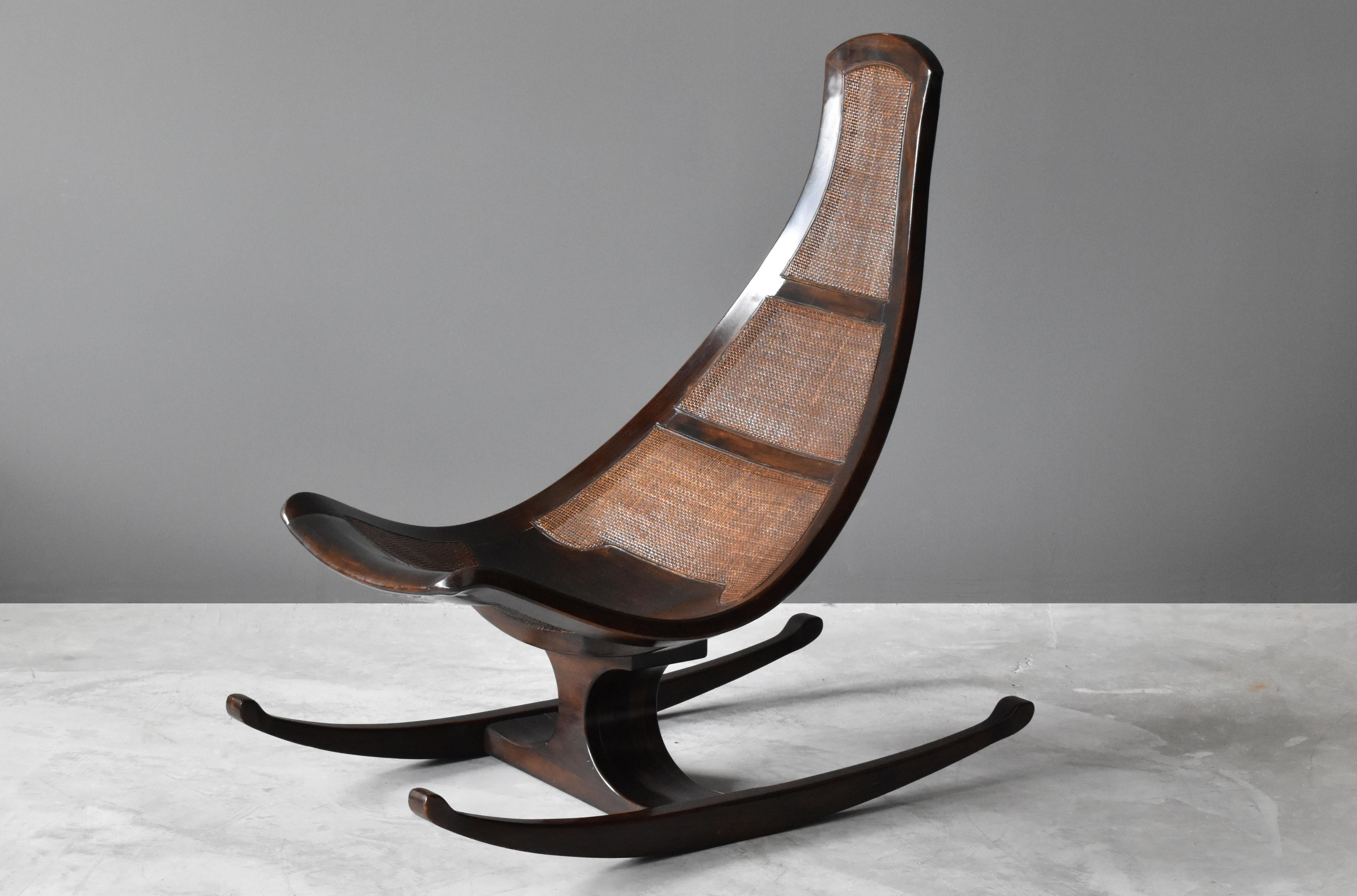 A highly modern and organic rocking lounge chair by an unknown modernist designer. Finely carved mahogany is paired with cane panels. Produced in Brazil, circa 1970s.

Other Brazilian designers include: Joaquim Tenreiro, Sergio Rodrigues, Zanine