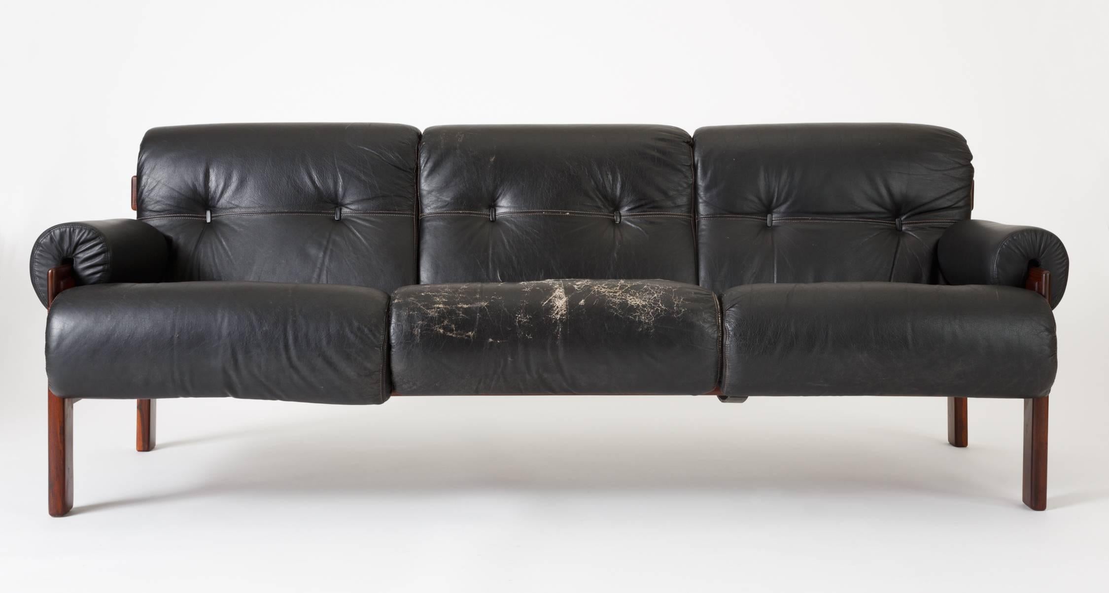 A three-seat sofa by Brazil-based Romanian designer Jean Gillon, produced by Italma in the 1960s. The sofa has a slatted frame of louro prieto wood - a dark tropical laurel with a straight grain pattern, strung with black leather straps. The