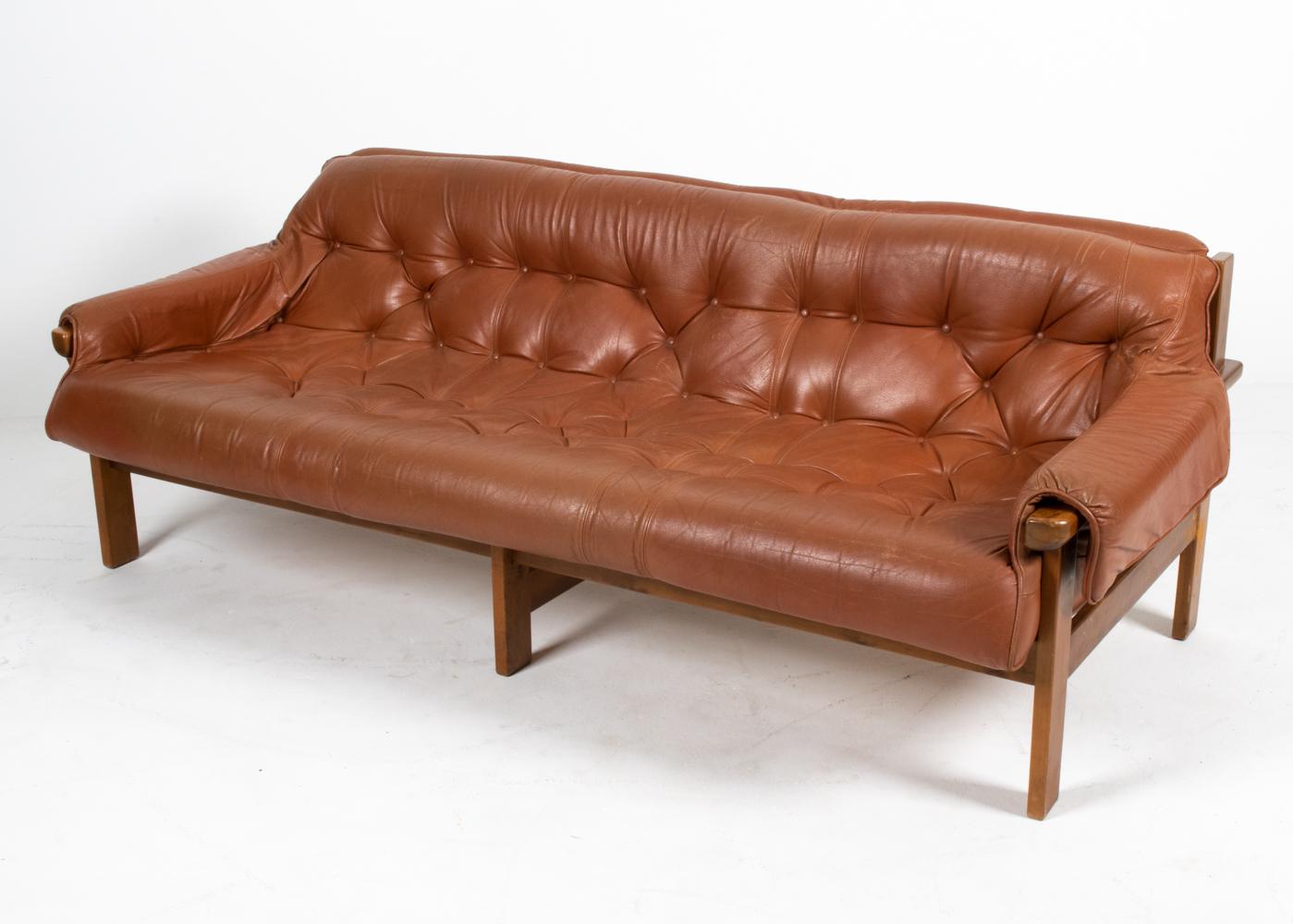 This fabulous sofa in the Brazilian Modernist style features a tufted cushion of brandy-colored bonded leather and a chunky solid wood frame. Though it is unsigned, the design is similar to that of Percival Lafer's MP-41 series. 

As one of the
