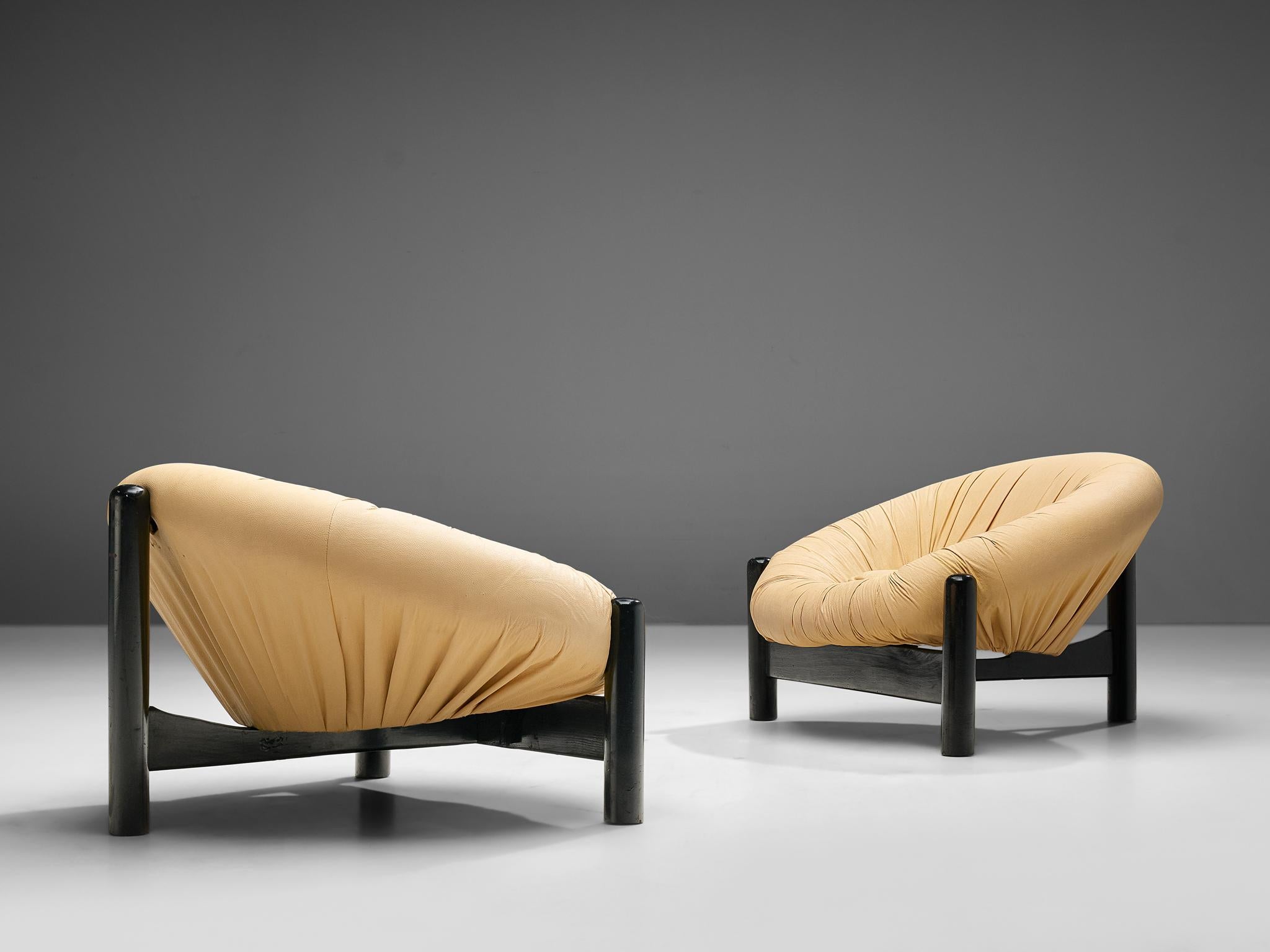 Pair of lounge chairs, leather, lacquered wood, Brazil, 1970s

This bulky Brazilian lounge chair consists of a round shell that forms a ring around the seat. The beige camel upholstery is tufted around the shell in dynamic folds. The shape invites