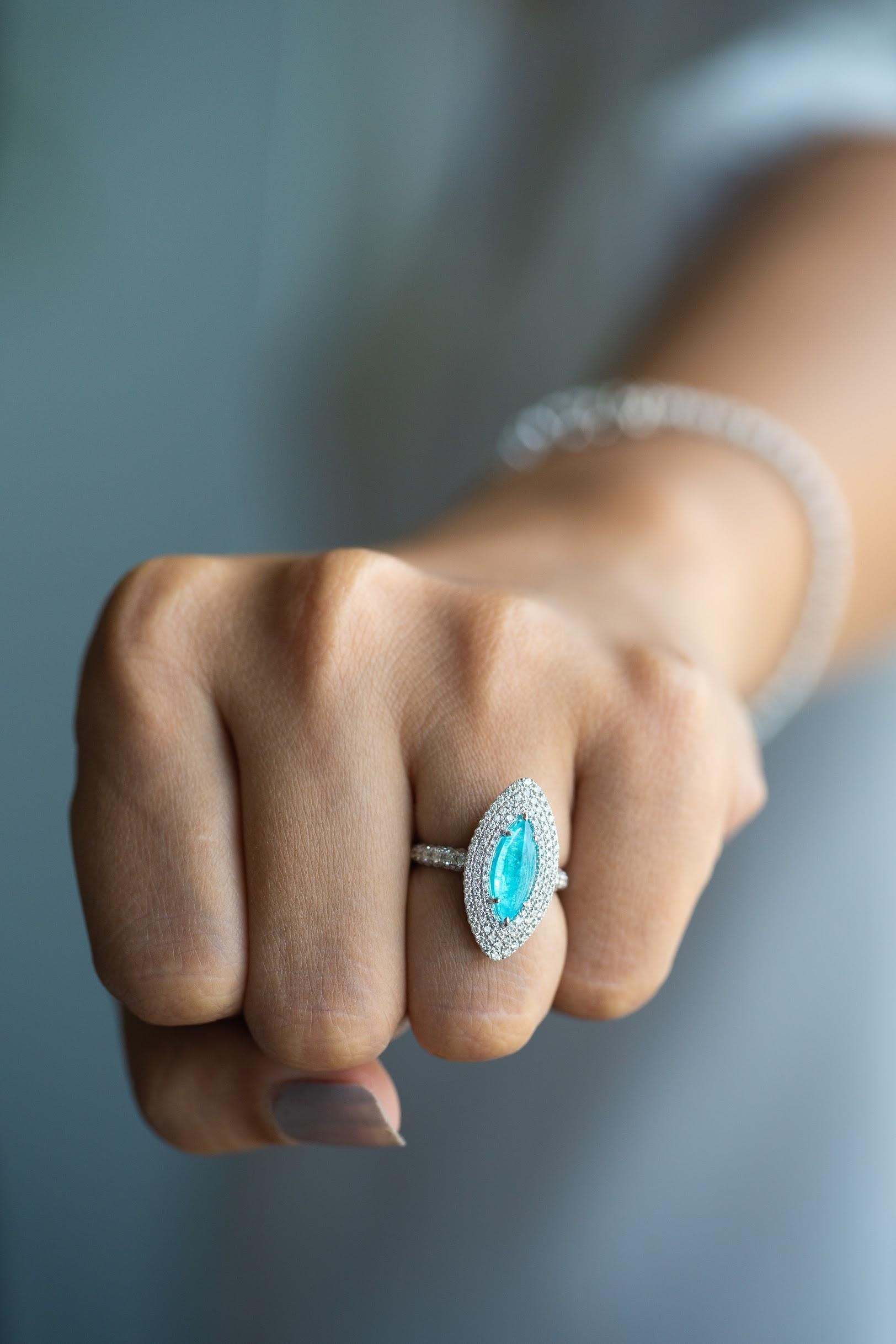 1 carat cabochon-cut bright blue paraiba ring surrounded by rows of sparkly pavé diamonds of highest quality (E/F color, VS quality). The ring’s shanks are also encrusted with diamond. Due to its small size, this paraiba is not certified when it