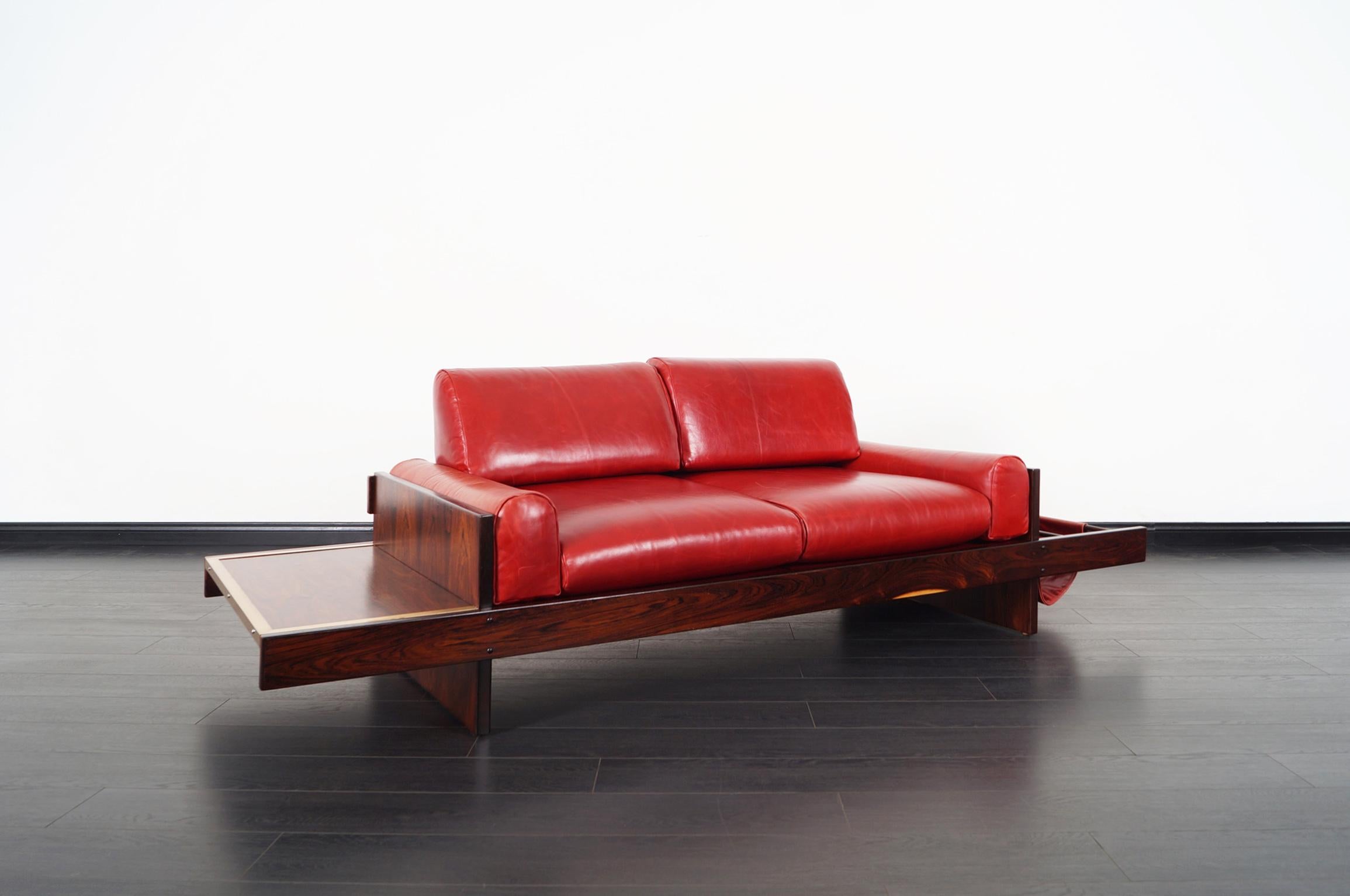 An incredibly unique vintage Brazilian rosewood and leather sofa attributed to Celina Moveis from Brazil, circa 1960s. The design in the structure of the sofa is fascinating, standing out in the center is four leather cushions, which contrast