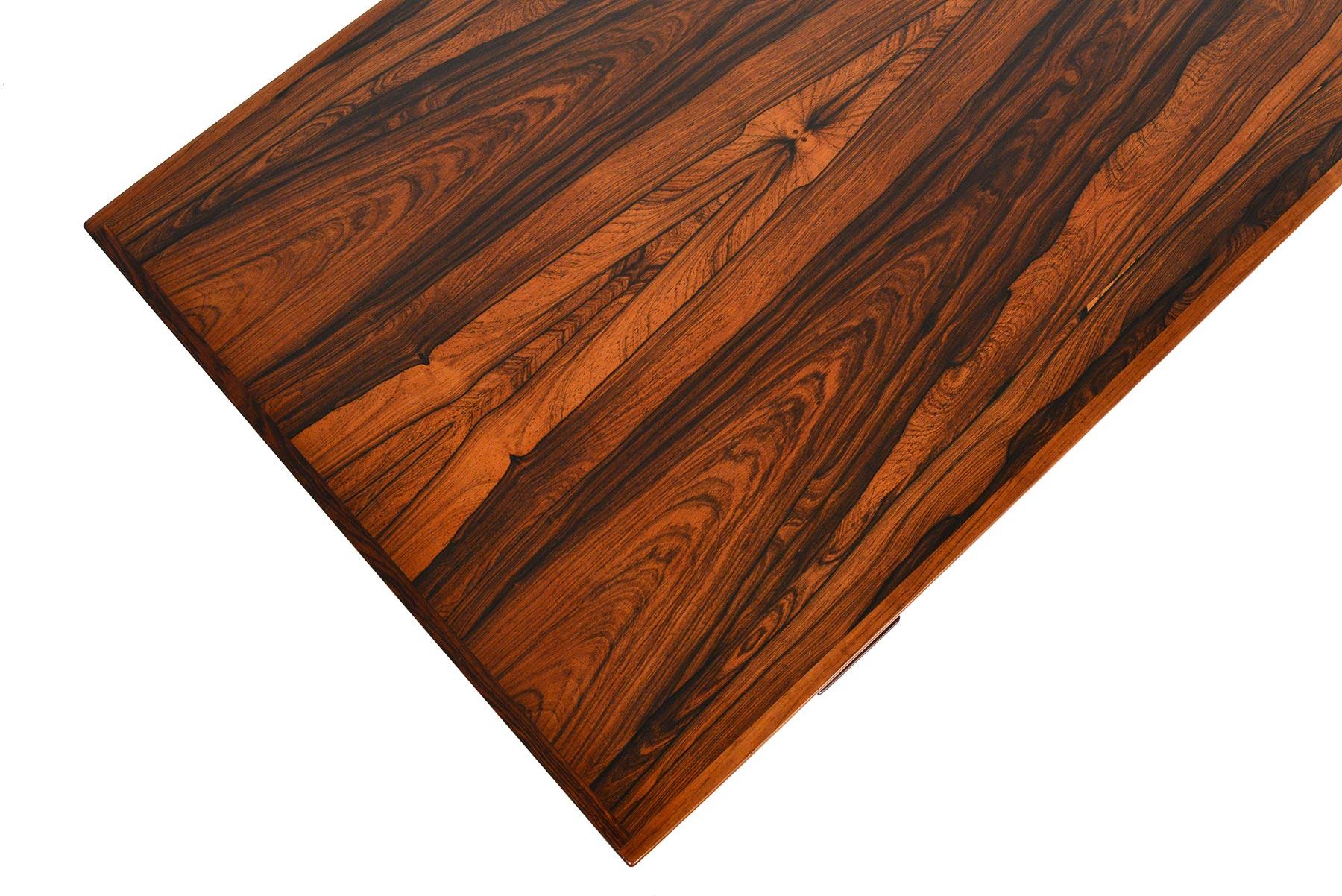 This Danish modern coffee table is crafted from beautiful Brazilian rosewood in a stunning book- matched design. This piece not only offers handsome lines and stately tapered legs, but a wonderfully functional pull- out black laminate serving tray.